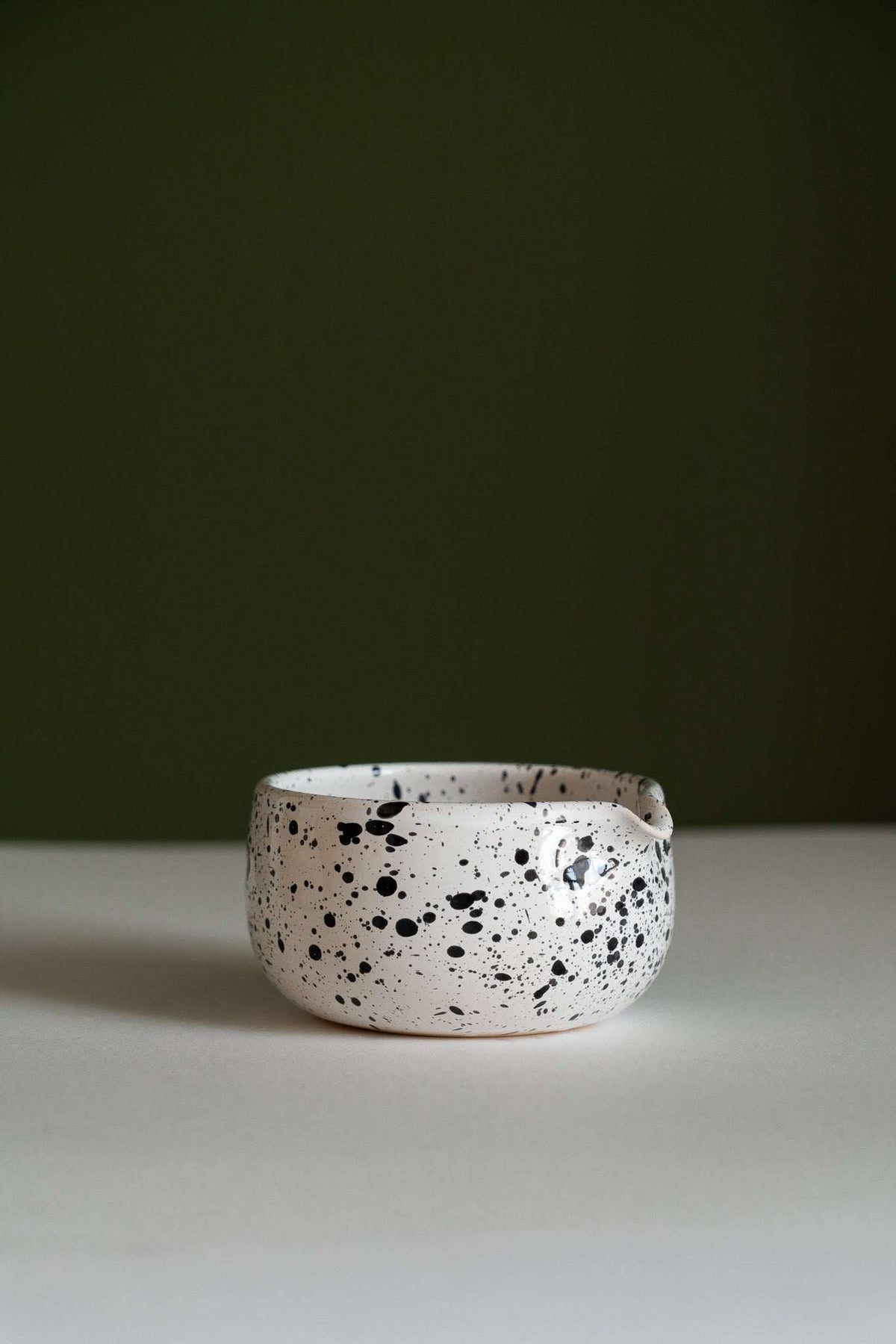 Handmade Matcha Bowl in white glazed stoneware, with dense black speckles and a rounded, low profile.