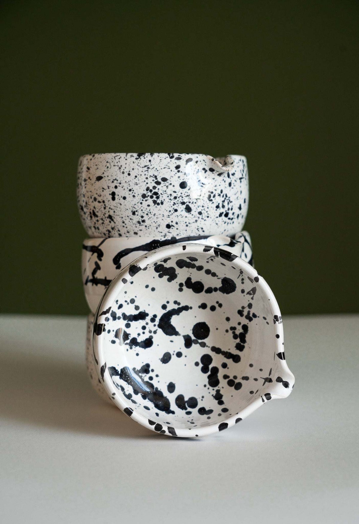 Handmade Matcha Bowl in white glazed stoneware, featuring bold black speckles and splashes with a rounded shape.
