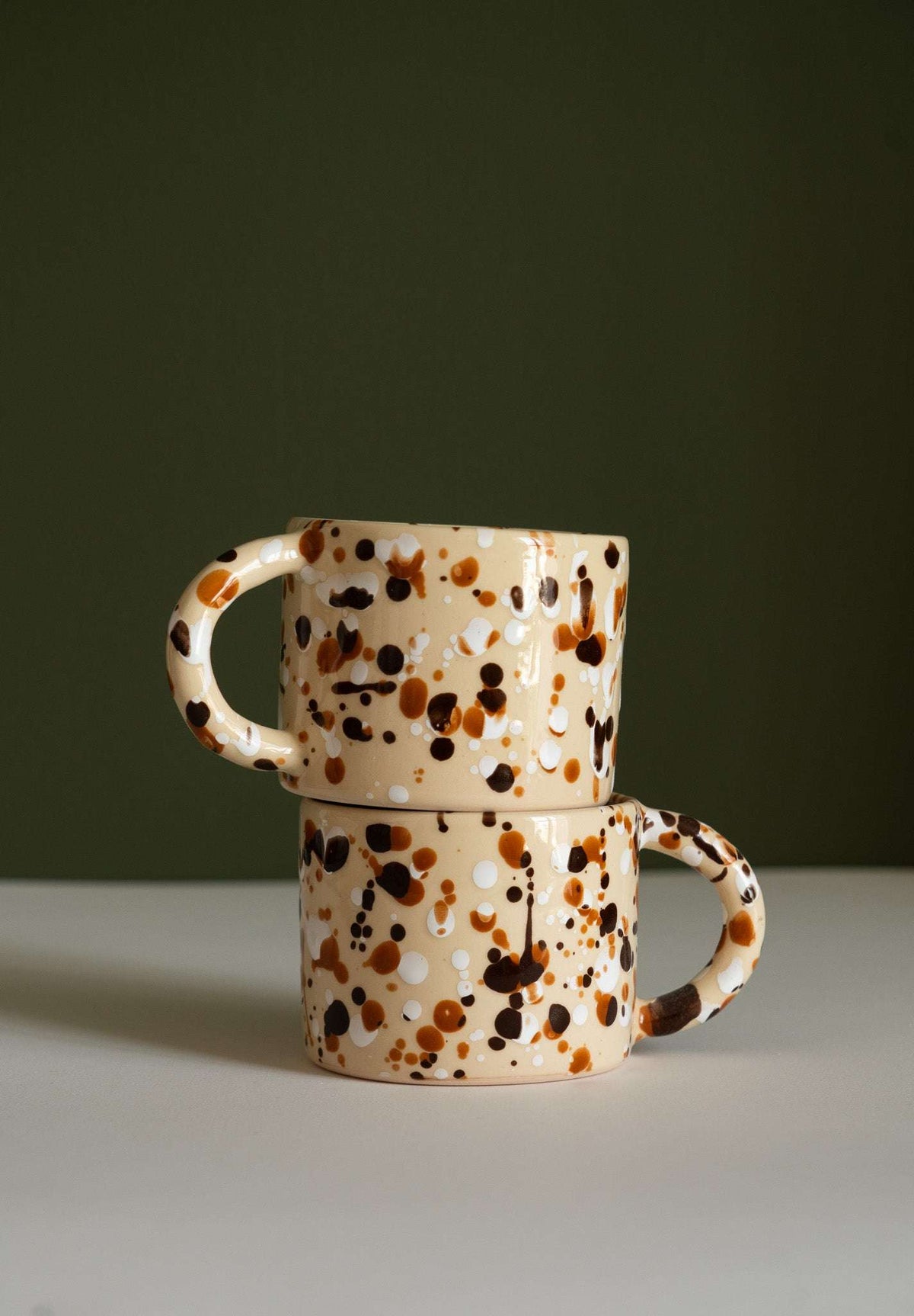 Splatter Stoneware Mug in cream ceramic with brown, black, and white speckles, featuring a rounded handle.