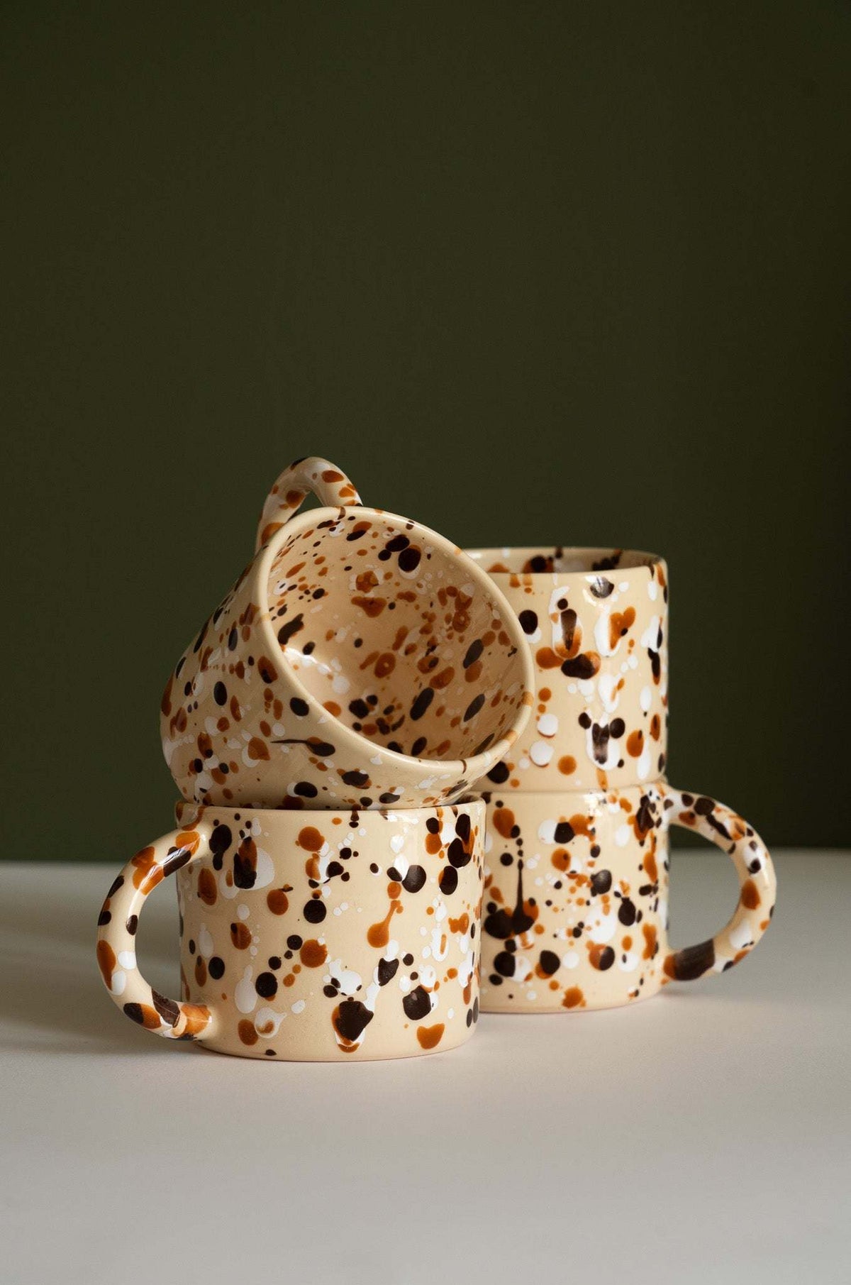 Splatter Stoneware Mug in cream ceramic with brown and black speckles, rounded handles, and a glossy finish.