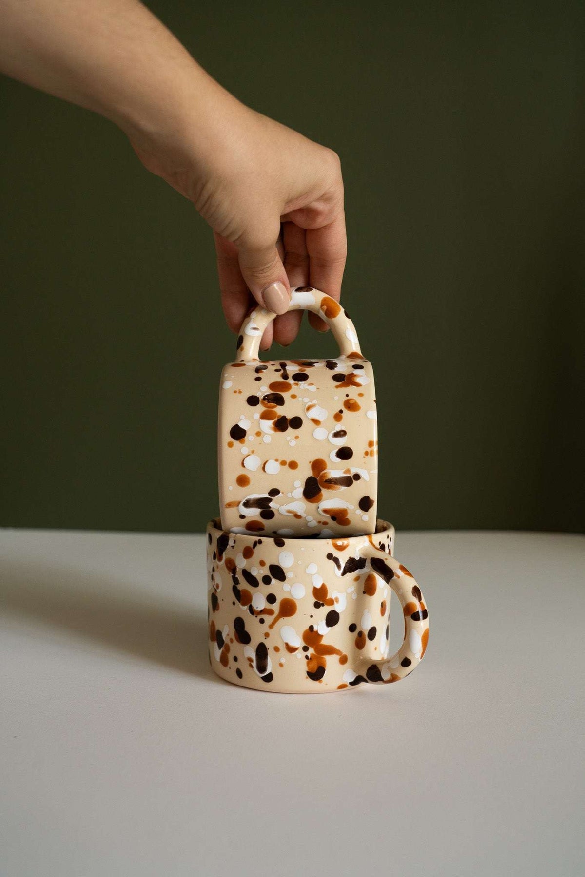 Splatter Stoneware Mug in glossy cream ceramic with caramel, brown, and black speckles, featuring a rounded handle.