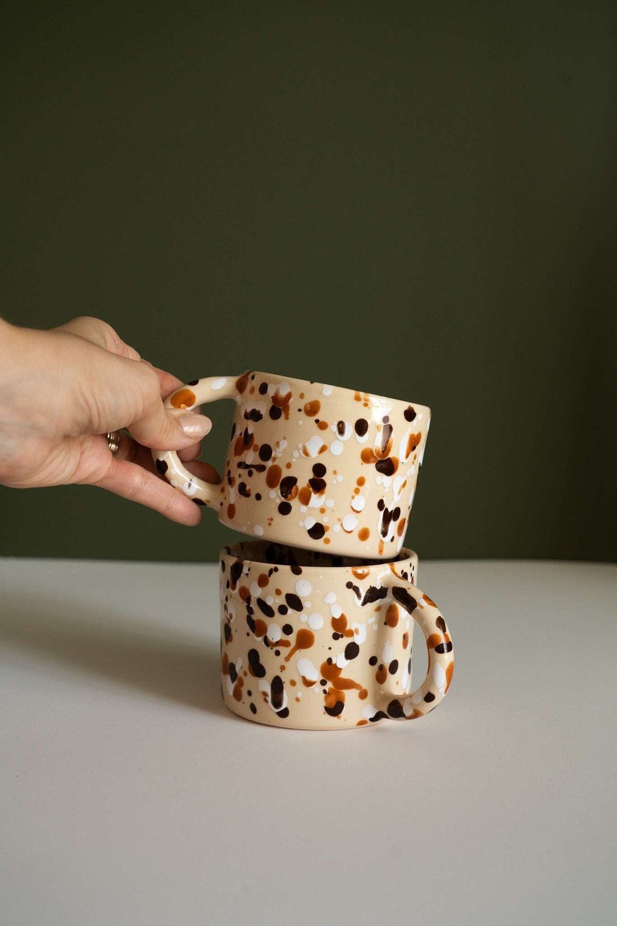 Splatter Stoneware Mug in cream ceramic with glossy brown and black speckles, rounded handle and straight sides.