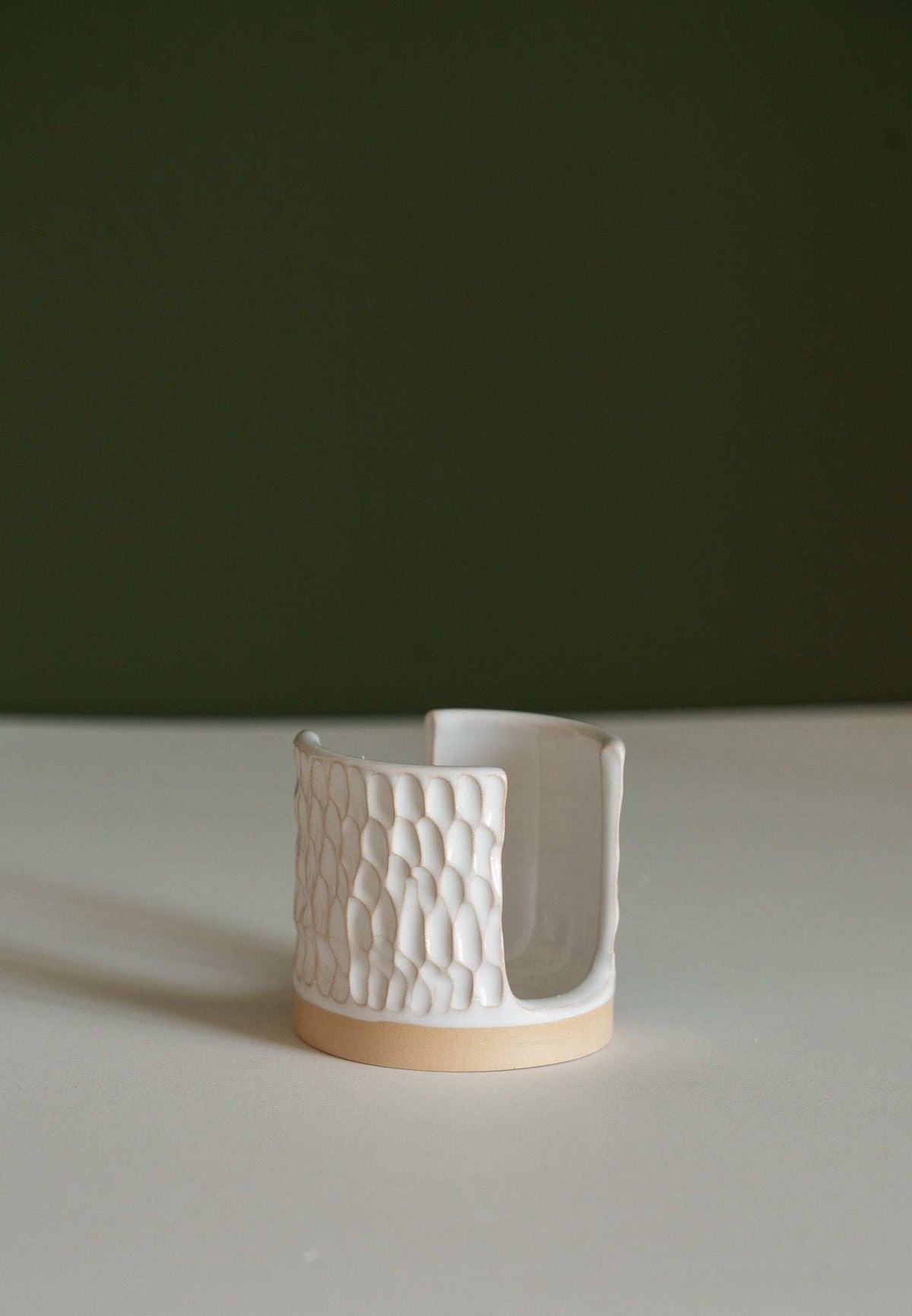 Handmade ceramic sponge holder with carved scallop design on kitchen sink