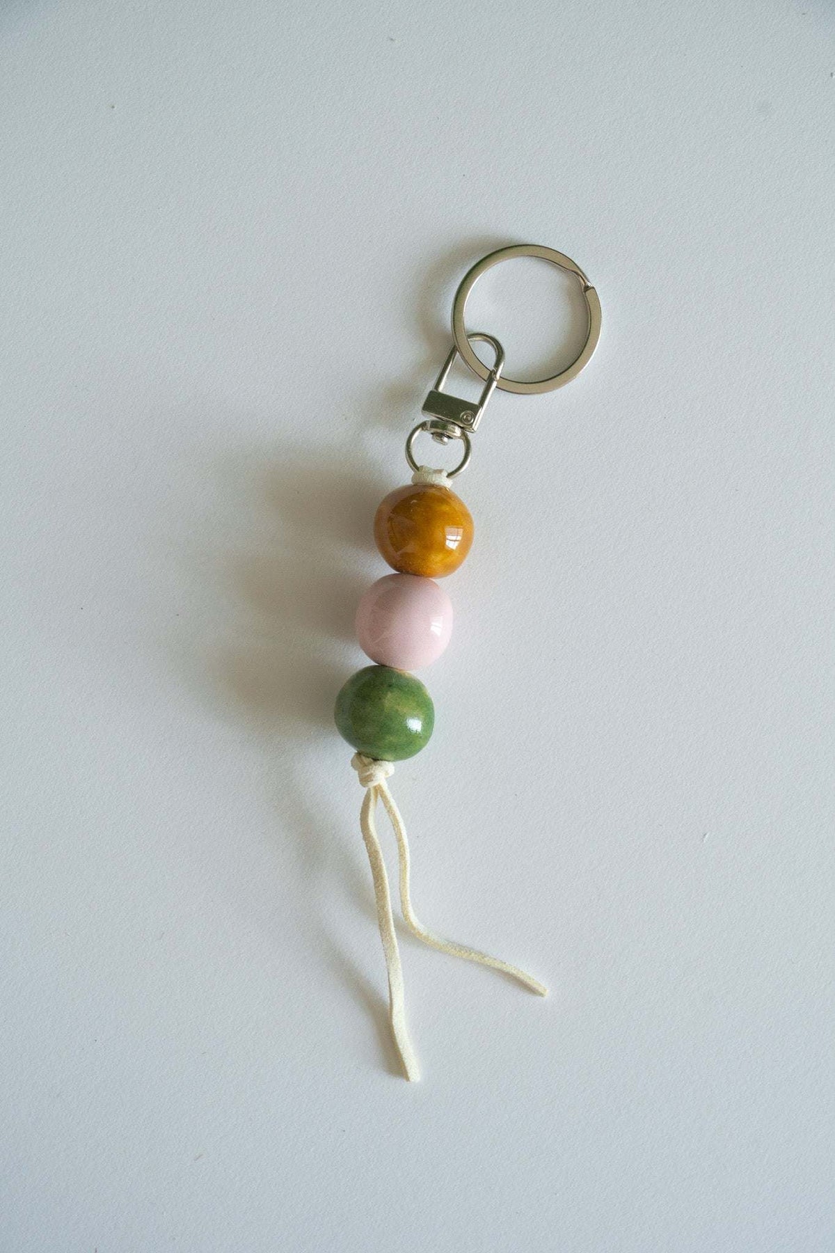 Handmade ceramic keychain with pastel pink, green, and caramel beads on leather cord
