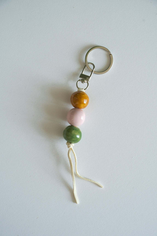 Handmade ceramic keychain with pastel pink, green, and caramel beads on leather cord
