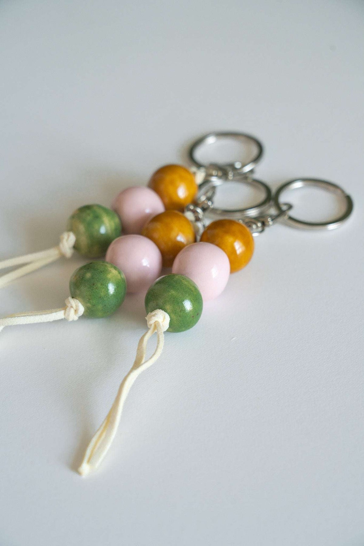 Handmade ceramic keychain with pastel pink, earthy green, and caramel beads on leather cord with silver hardware