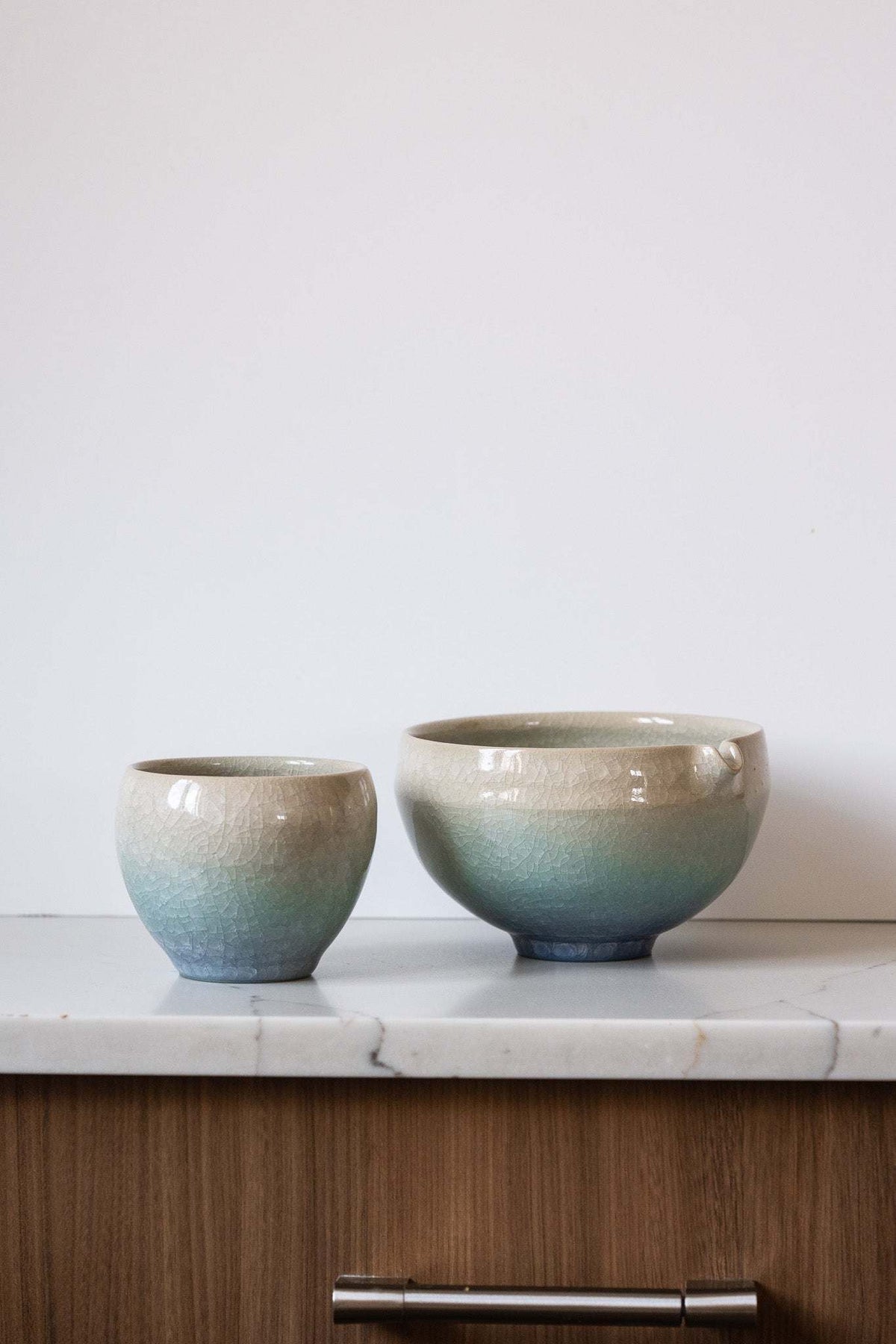 Ceramic Matcha Bowl and matching cup in handmade stoneware, with sandy cream-to-muted blue-green gradient glaze and crackle texture.