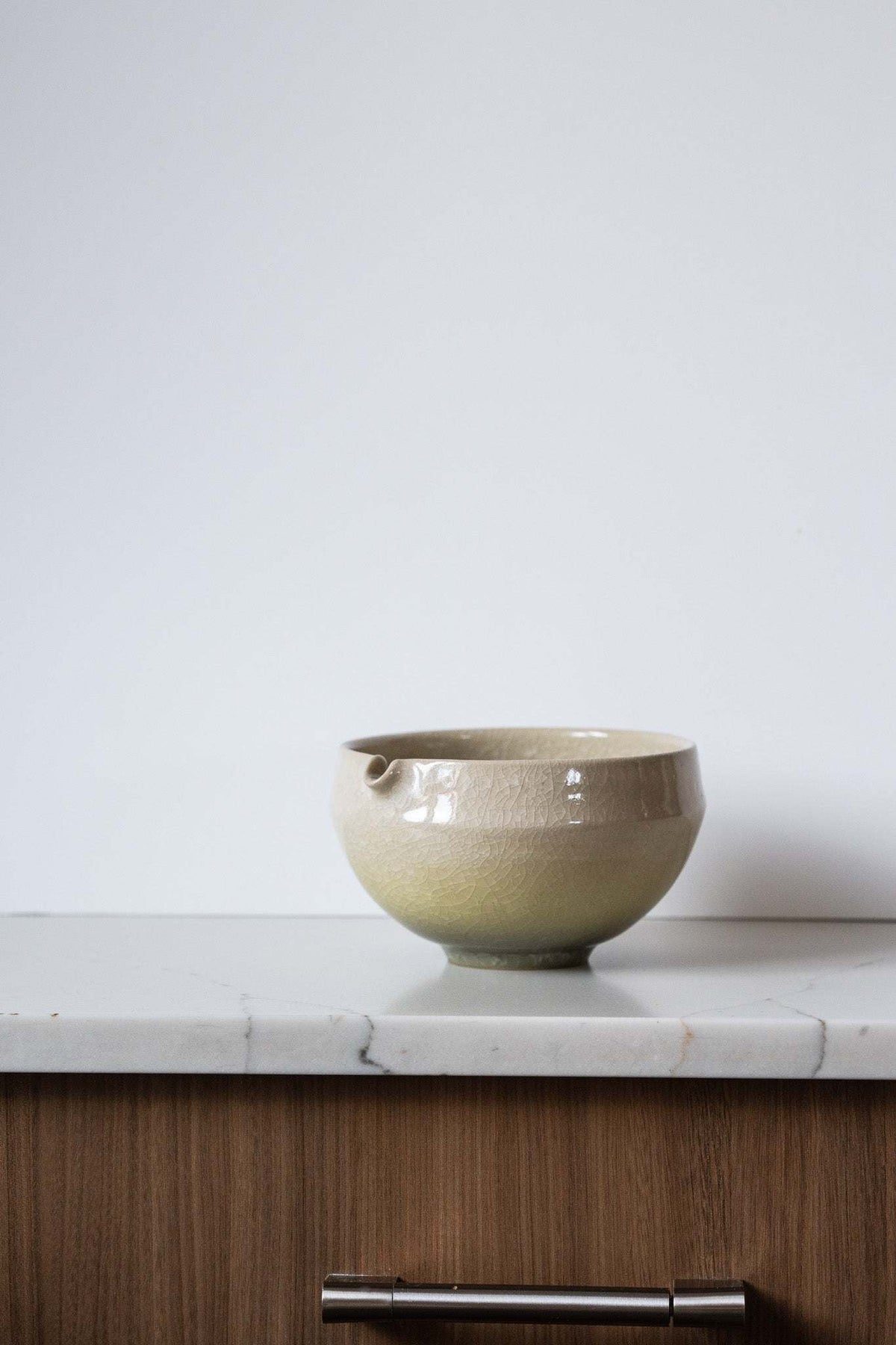 Ceramic Matcha Bowl in glossy pale sage and cream stoneware, with a rounded form and small pouring spout.