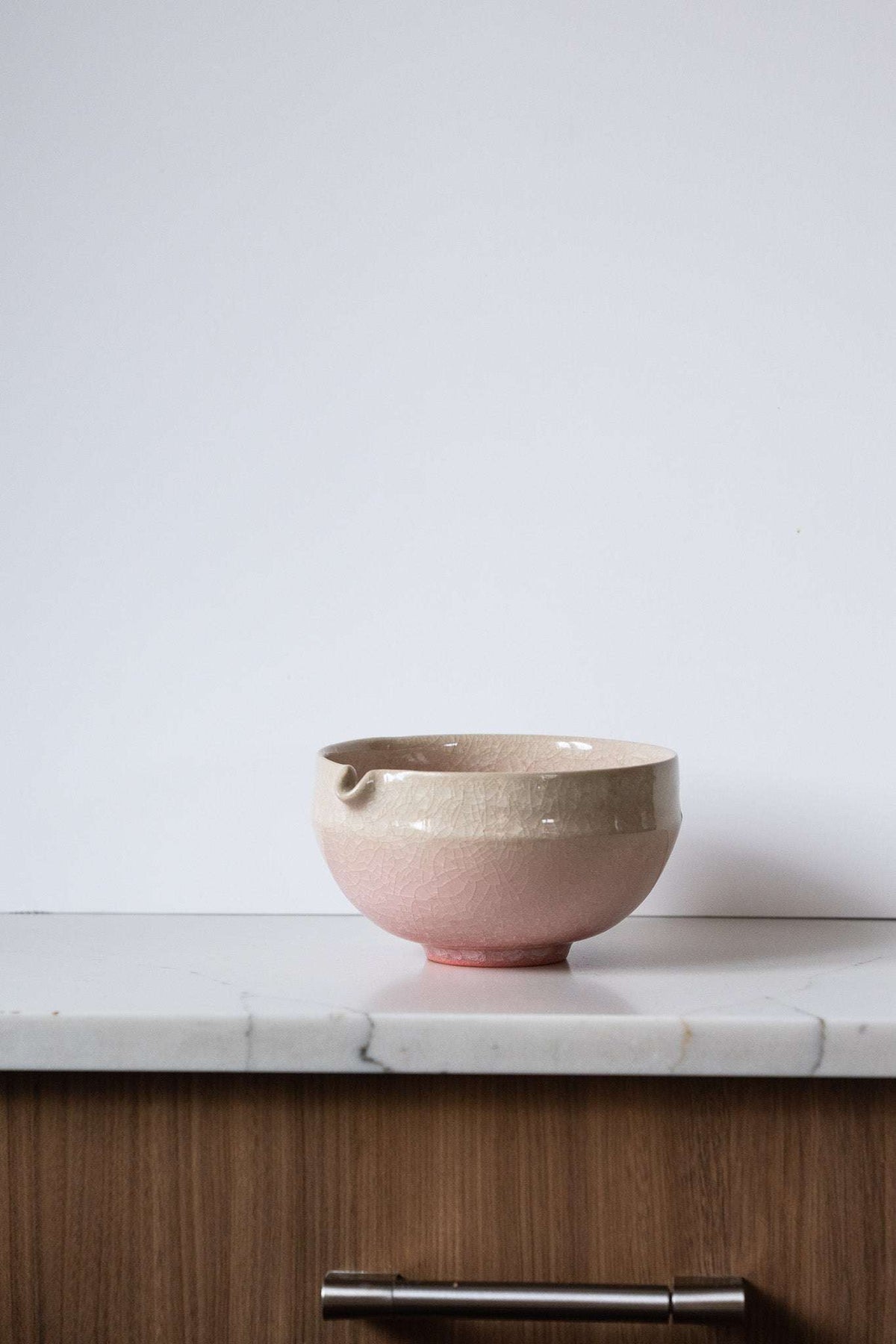 Ceramic Matcha Bowl in blush pink and sandy cream stoneware, with a glossy crackle glaze and built-in pouring spout.