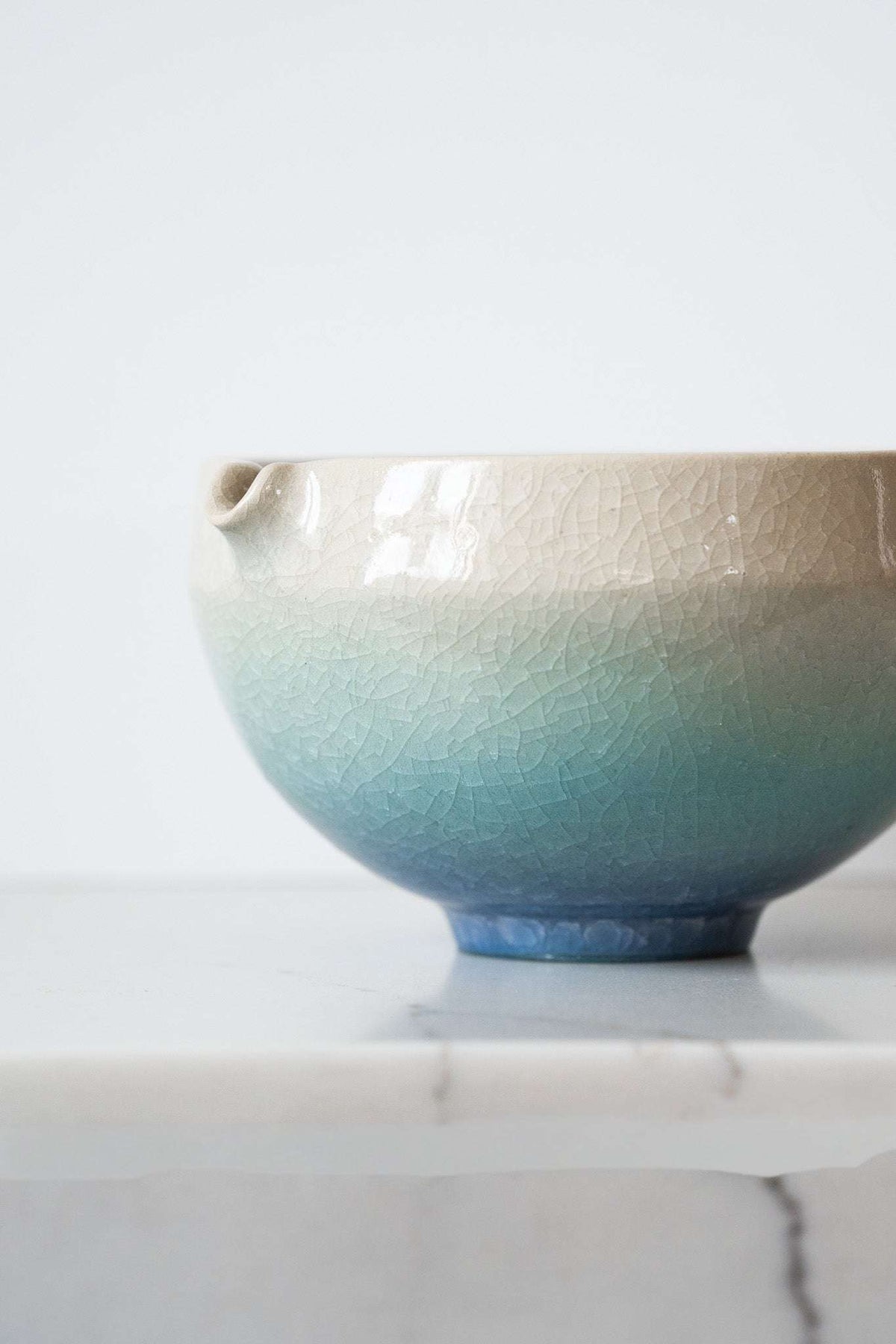Ceramic Matcha Bowl in cream fading to seafoam blue, with a glossy crackle glaze and built-in pouring spout.