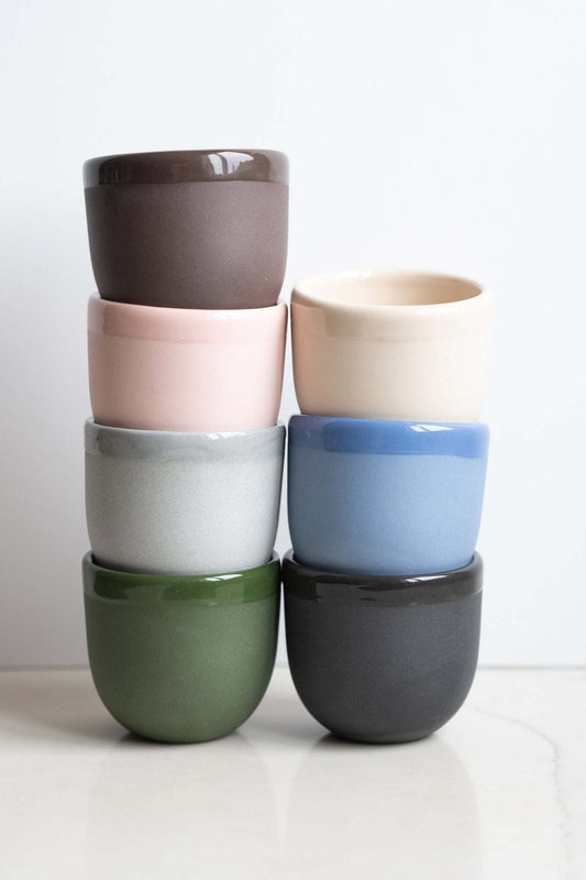 Porcelain Espresso Cup set of six matte porcelain cups in taupe, pink, cream, pale gray, green, and blue with contrasting rims.