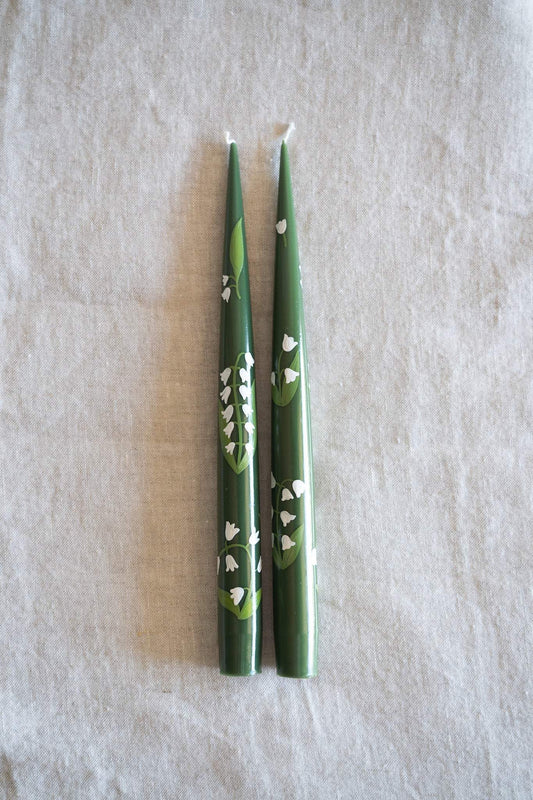 Hand-Painted Taper Candle set in deep green wax, decorated with delicate white hand-painted floral motifs and pointed tips.
