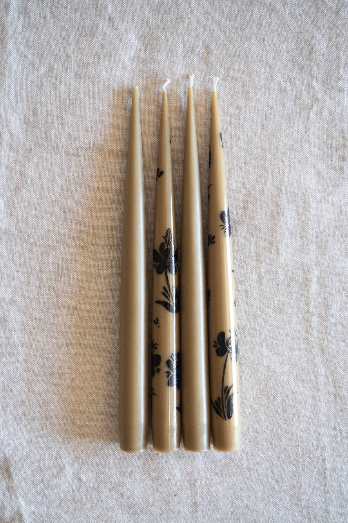 Hand-Painted Taper Candle Set of four slim beige candles with black hand-painted floral motifs and white wicks.