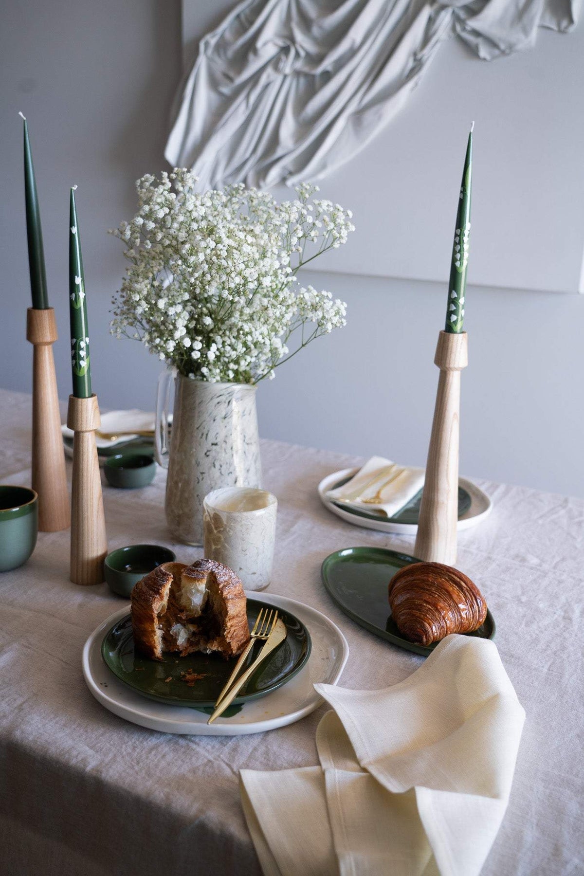 Hand-Painted Taper Candle set with slender dark green candles in natural wood holders, featuring a subtle cream dotted pattern.