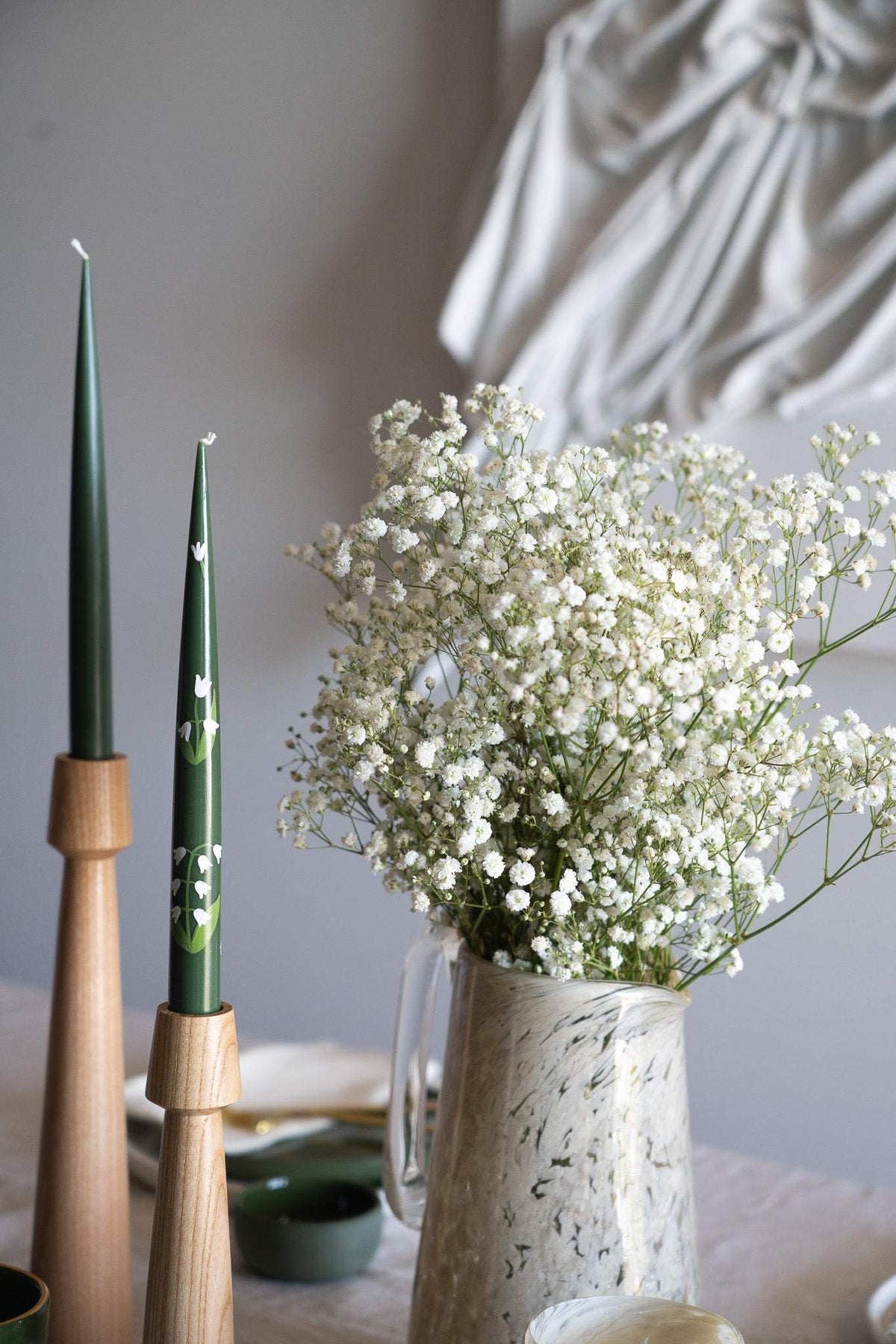 Hand-Painted Taper Candle pair in dark green with delicate white floral motifs and warm wooden holders.