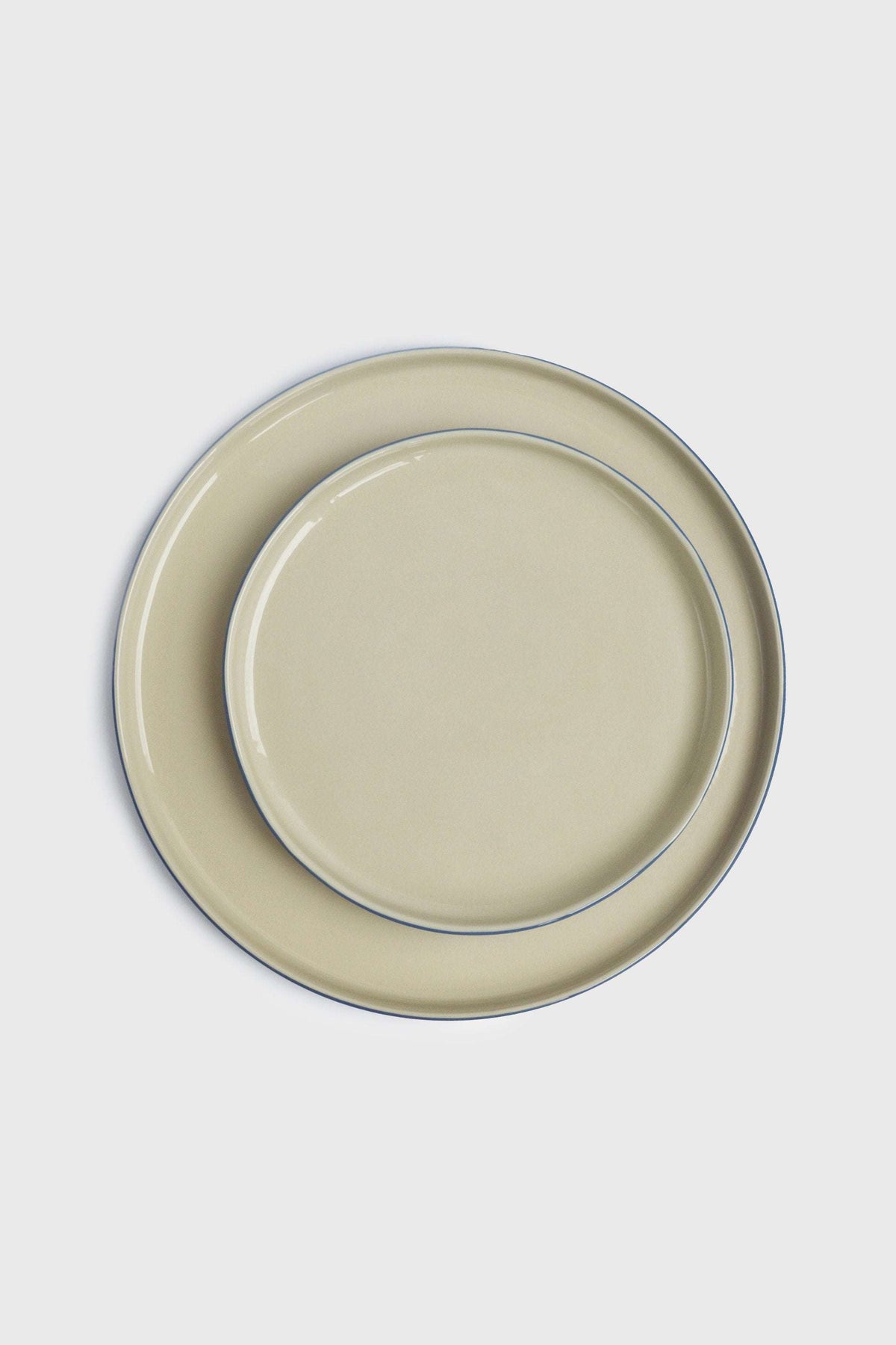 Dinner plates in Handmade Blue Porcelain with a pale beige glaze and fine blue rim accents, shown in two sizes.