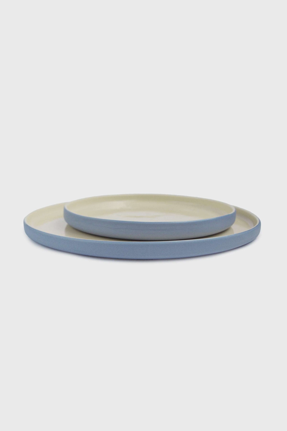 Handmade Blue Porcelain dinner plates in soft blue with pale cream glazed centers and smooth, rounded rims.