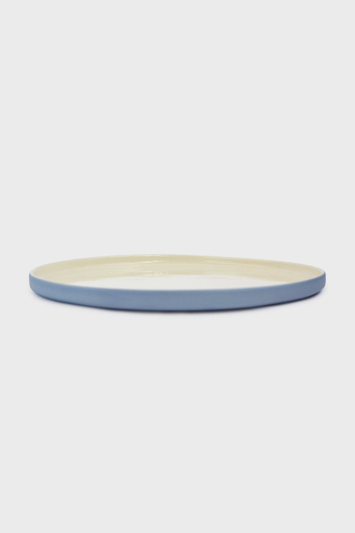 Dinner plate in Handmade Blue Porcelain with a pale blue exterior, cream glazed center, and smooth solid-color finish.