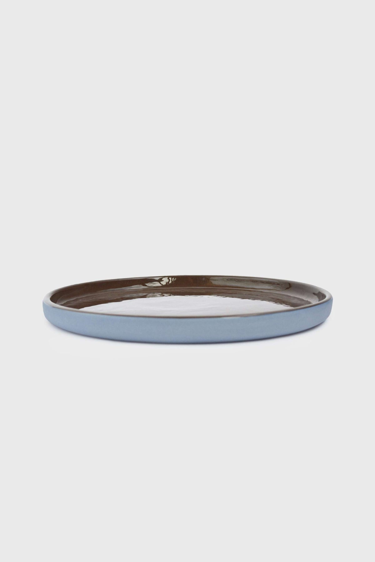 Handmade Blue Porcelain dinner plate with a pale blue exterior, white center, and glossy chocolate-brown rim glaze.