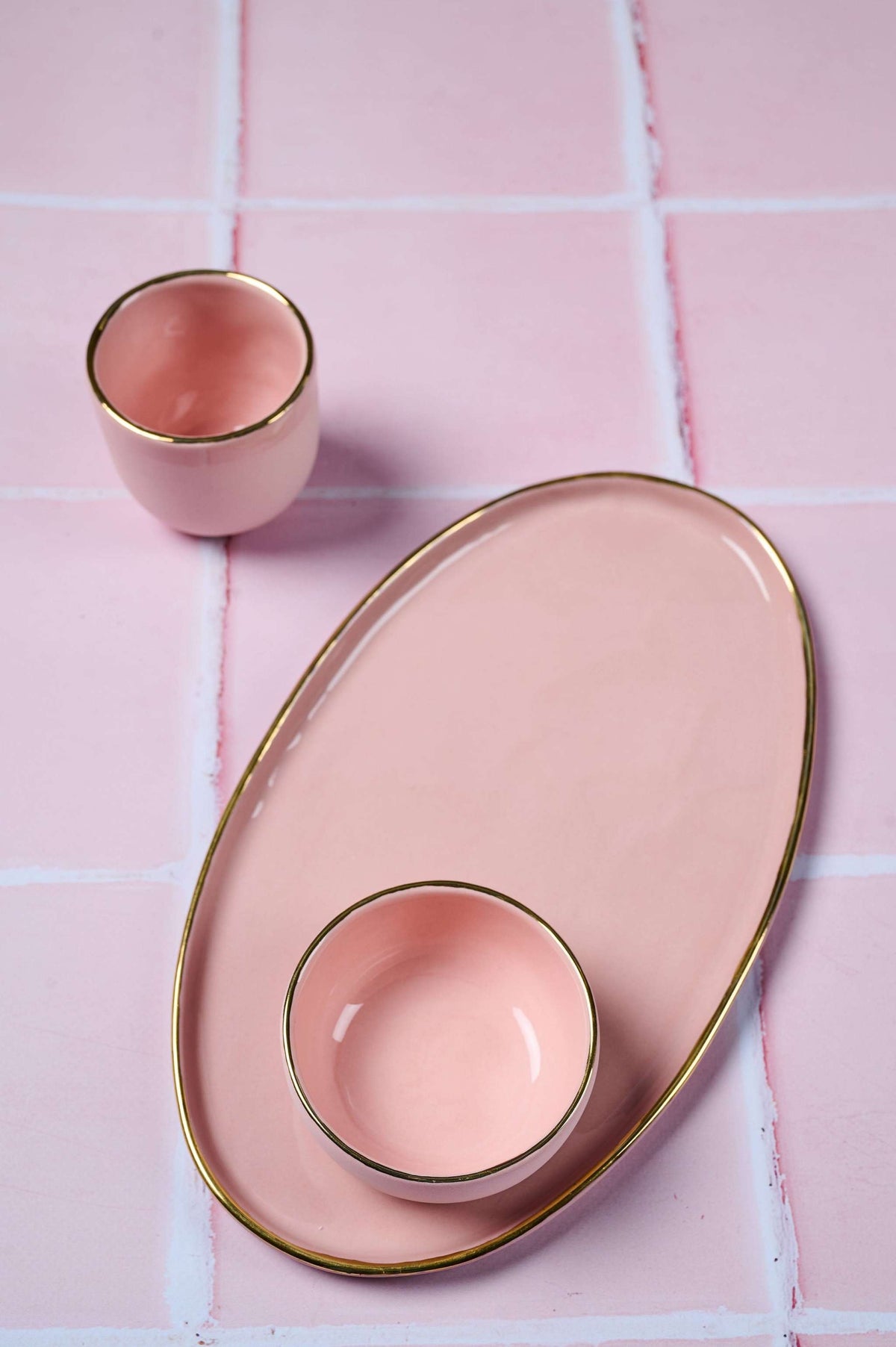 Handmade oval porcelain serving platter in powder pink with gold rim and organic edges