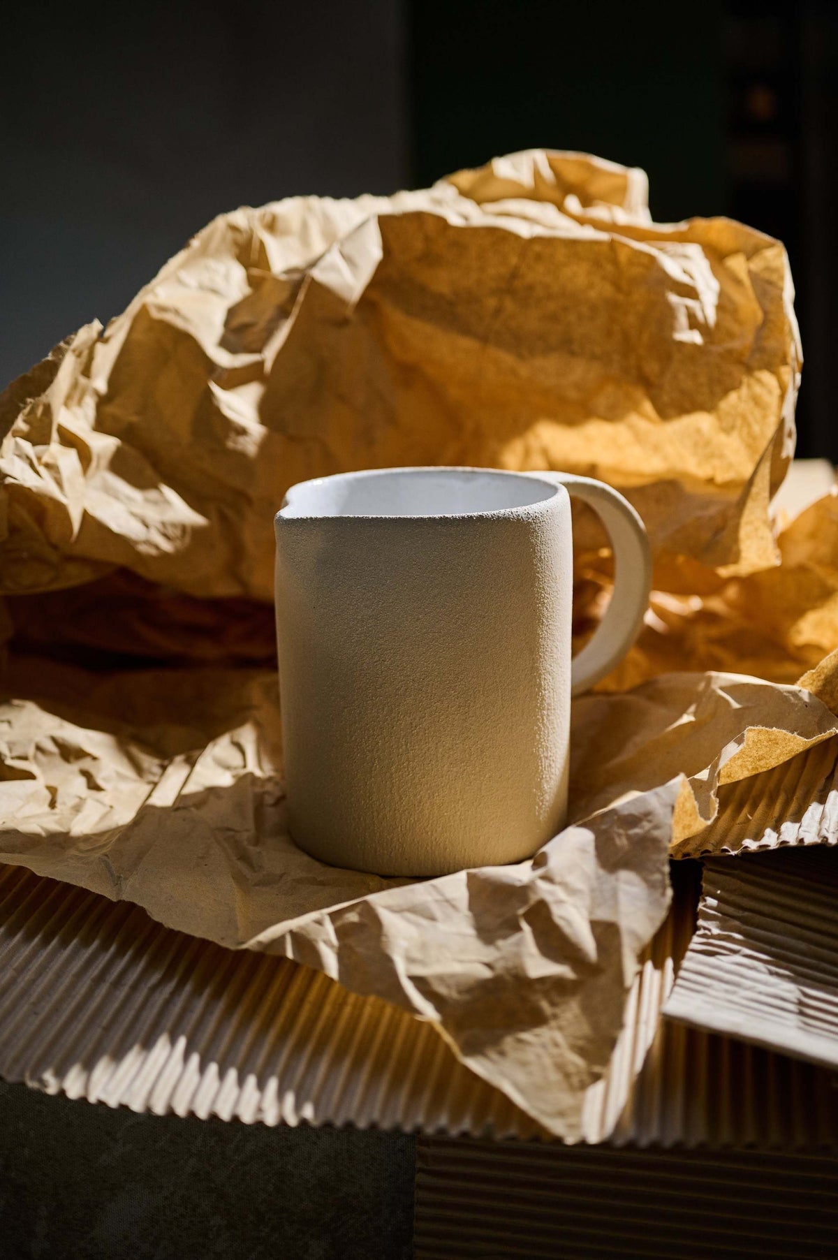 Handmade stoneware pitcher with natural rough texture and white glazed interior, made in Ukraine