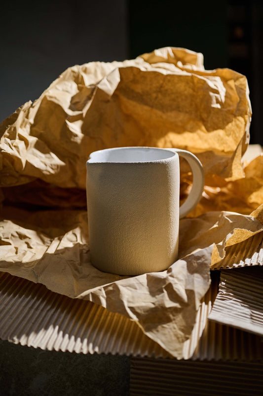 Handmade stoneware pitcher with natural rough texture and white glazed interior, made in Ukraine