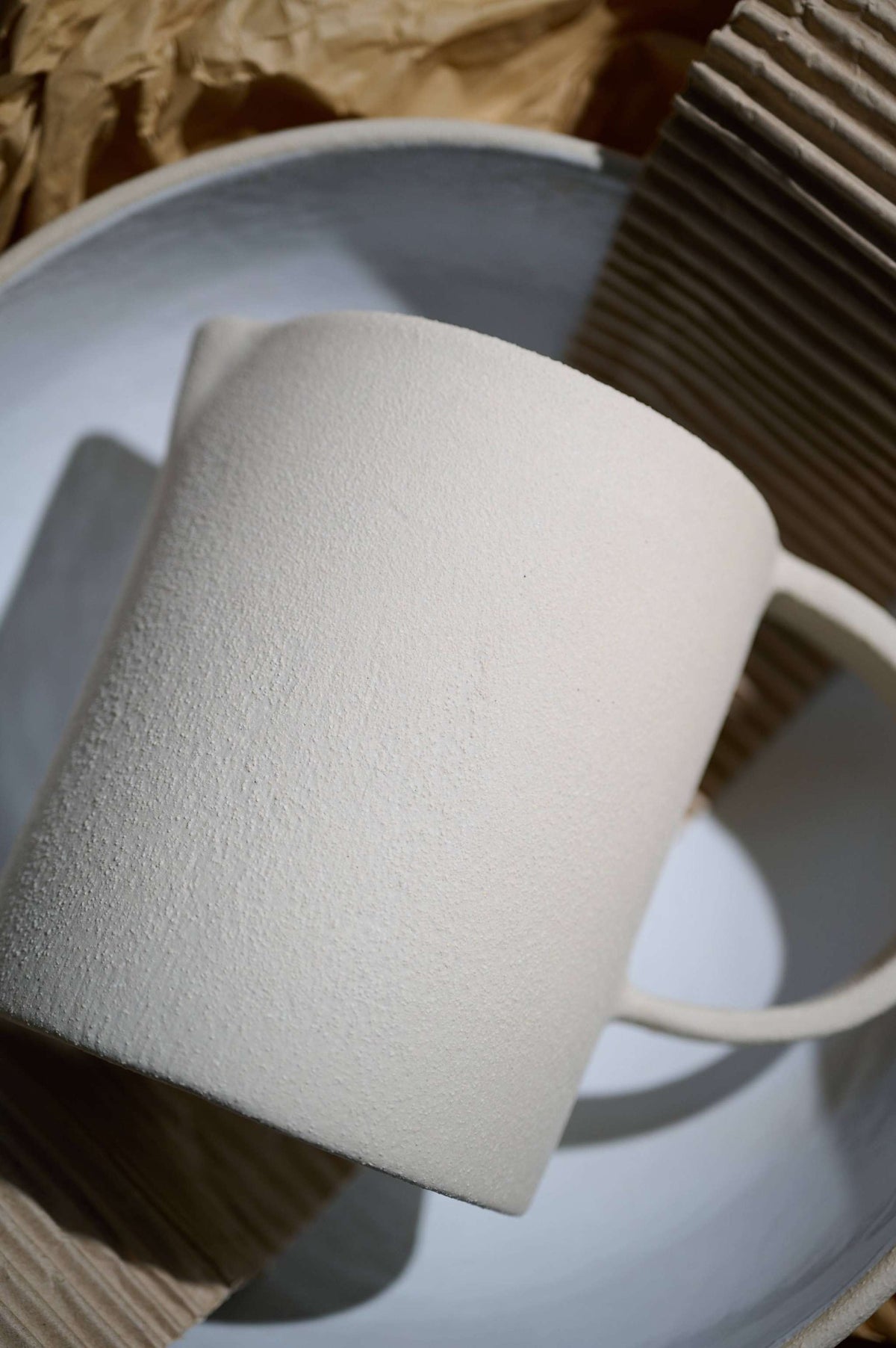 Handmade stoneware pitcher with rough texture and white glazed interior, made in Ukraine
