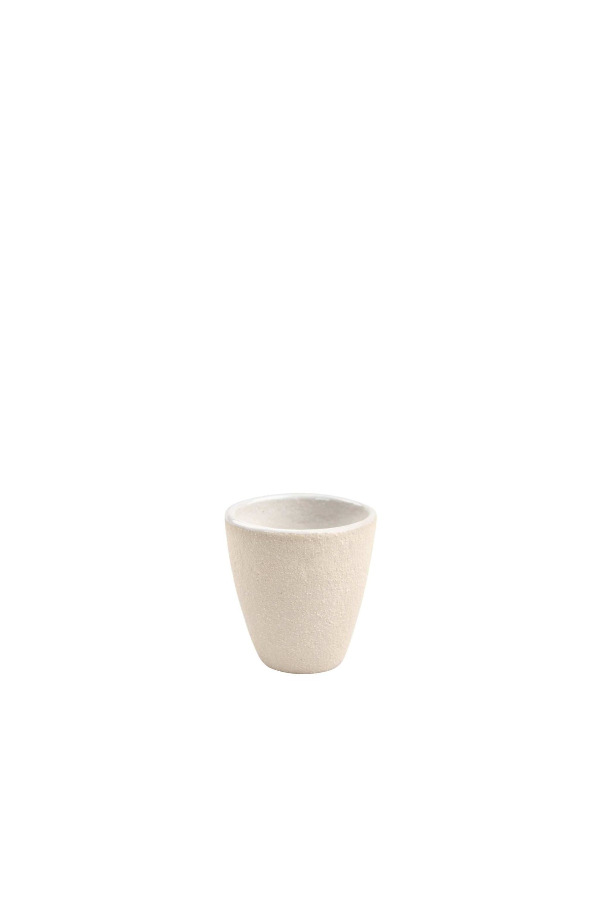 Handmade stoneware espresso cup with exposed clay exterior and white glazed interior on a wooden surface