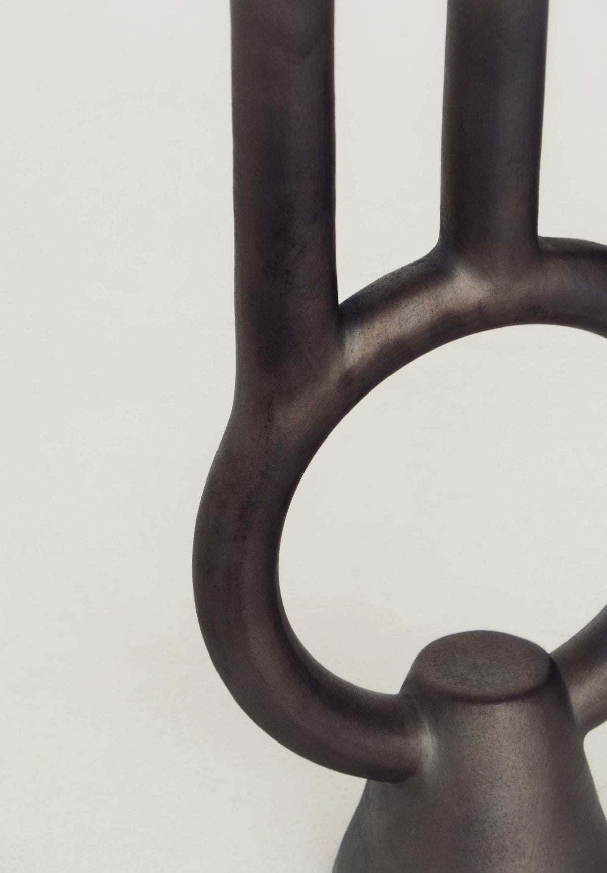 Smoke-fired ceramic black candle holder casting deep shadows, handmade in Ukraine