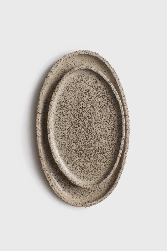 Large Serving Platter in creamy beige stoneware with dense black speckles, oval shape and raised rim.