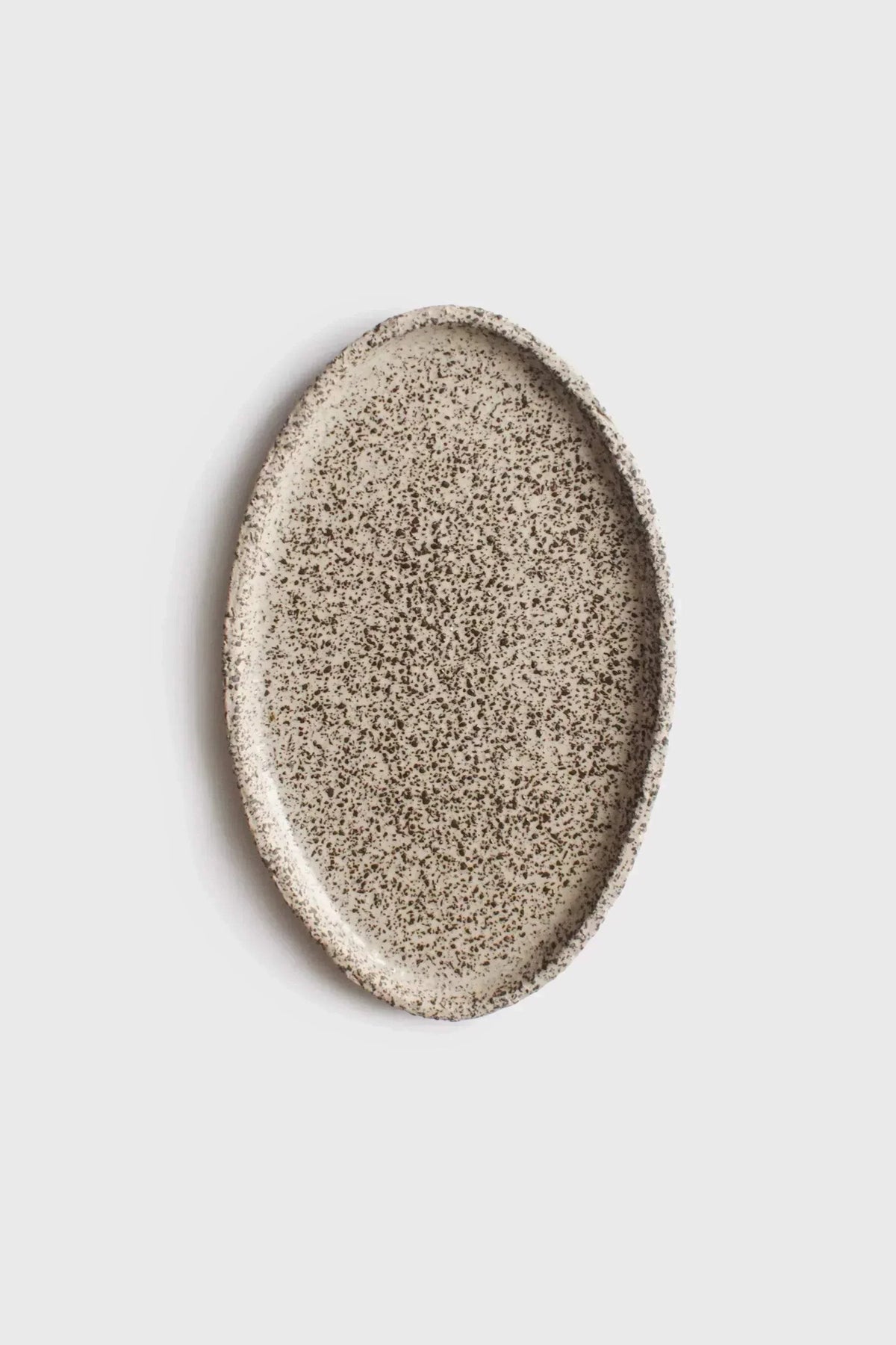 Large Serving Platter in creamy white stoneware with dense black speckles, featuring a hand-shaped oval form and raised rim.