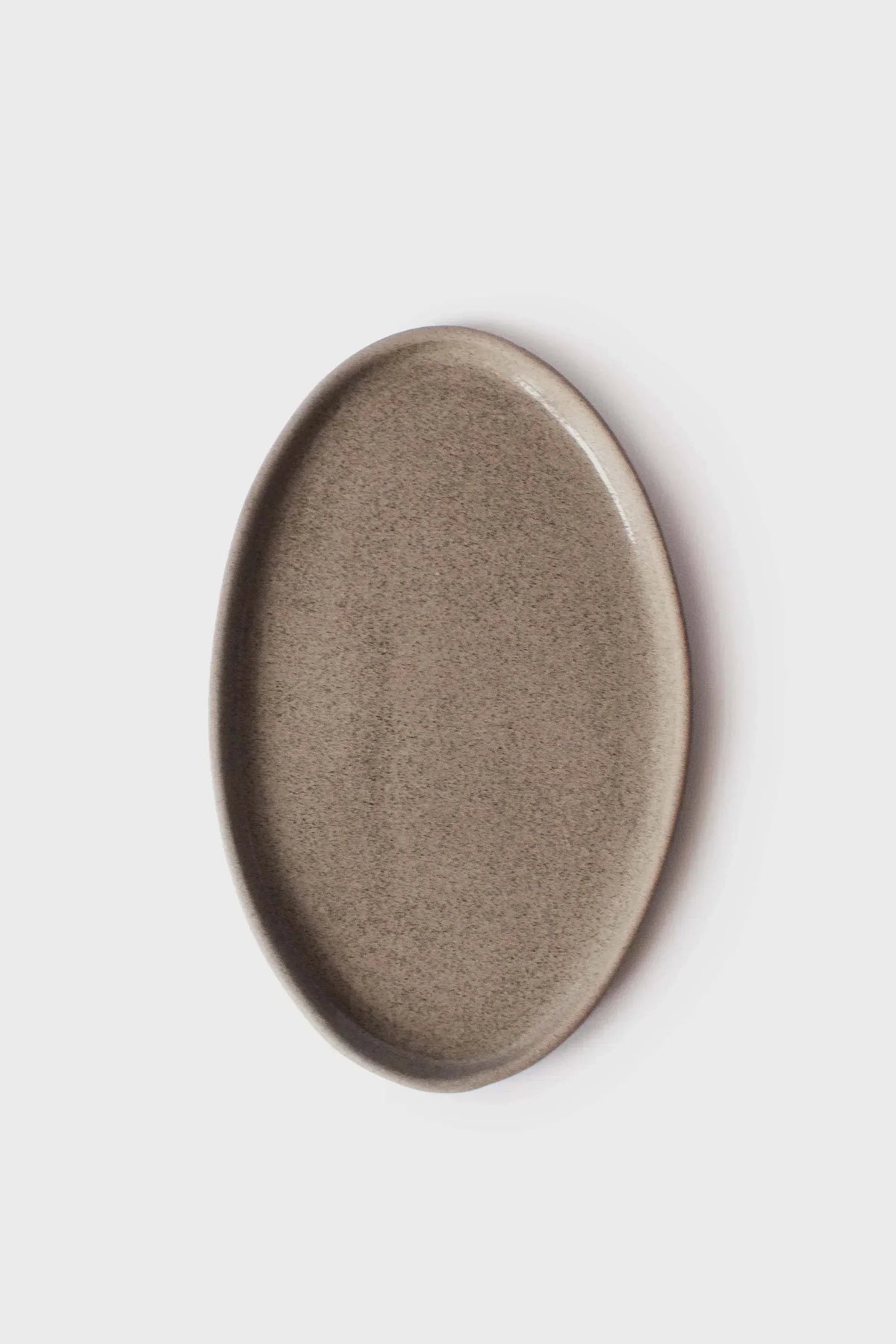 Serving platter in Handmade Stoneware, oval taupe-gray with a speckled concrete-like glaze and raised rim.
