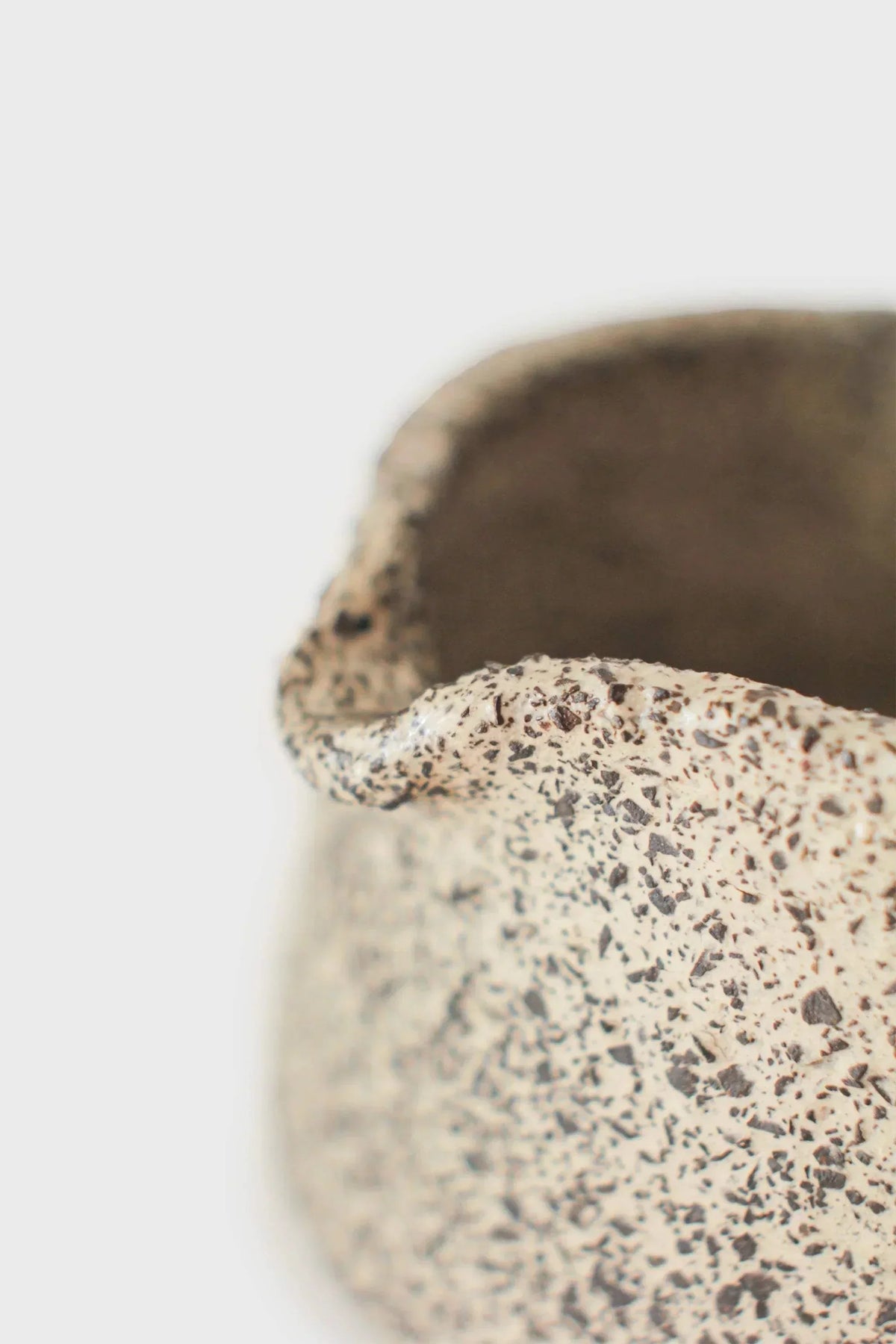 Handmade Stoneware Matcha Bowl in cream with dense dark speckles, a rough tactile finish, and a pinched pouring lip.