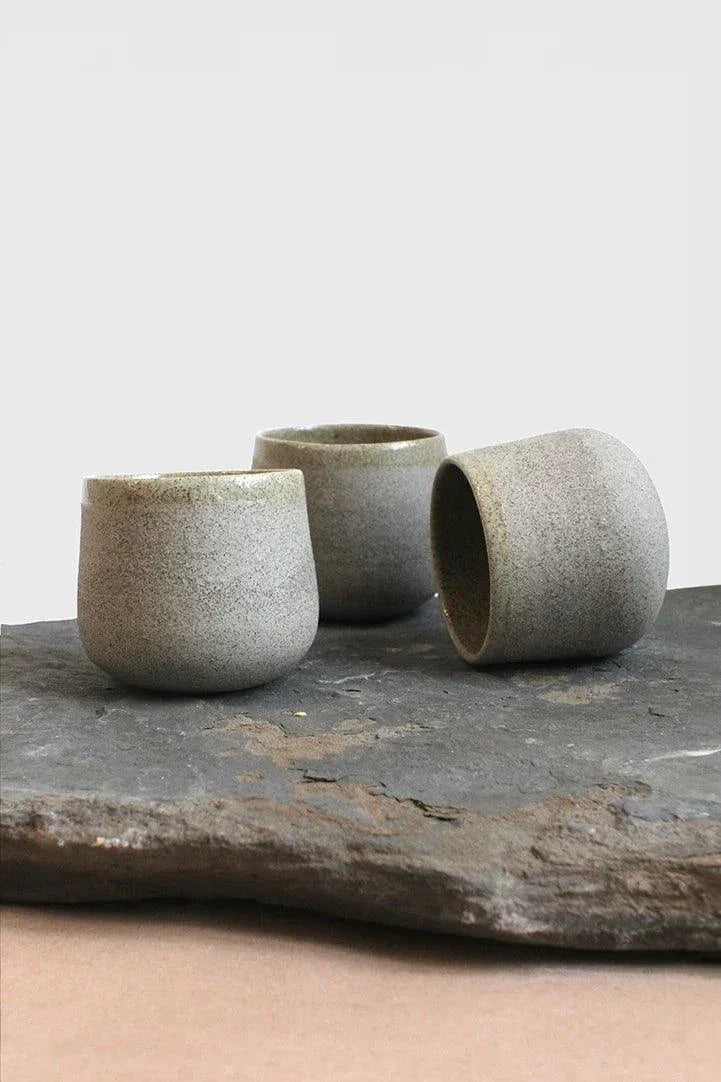 Handmade Stoneware Coffee Cup in speckled gray with a rough matte exterior, rounded shape, and dark glazed interior.