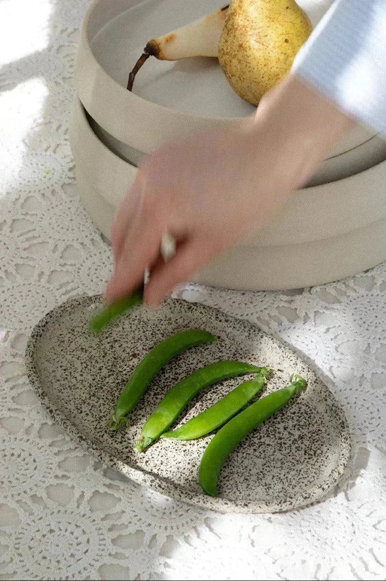 Large Serving Platter in oval handmade stoneware, creamy white with dense black speckles and a smooth, organic rim.