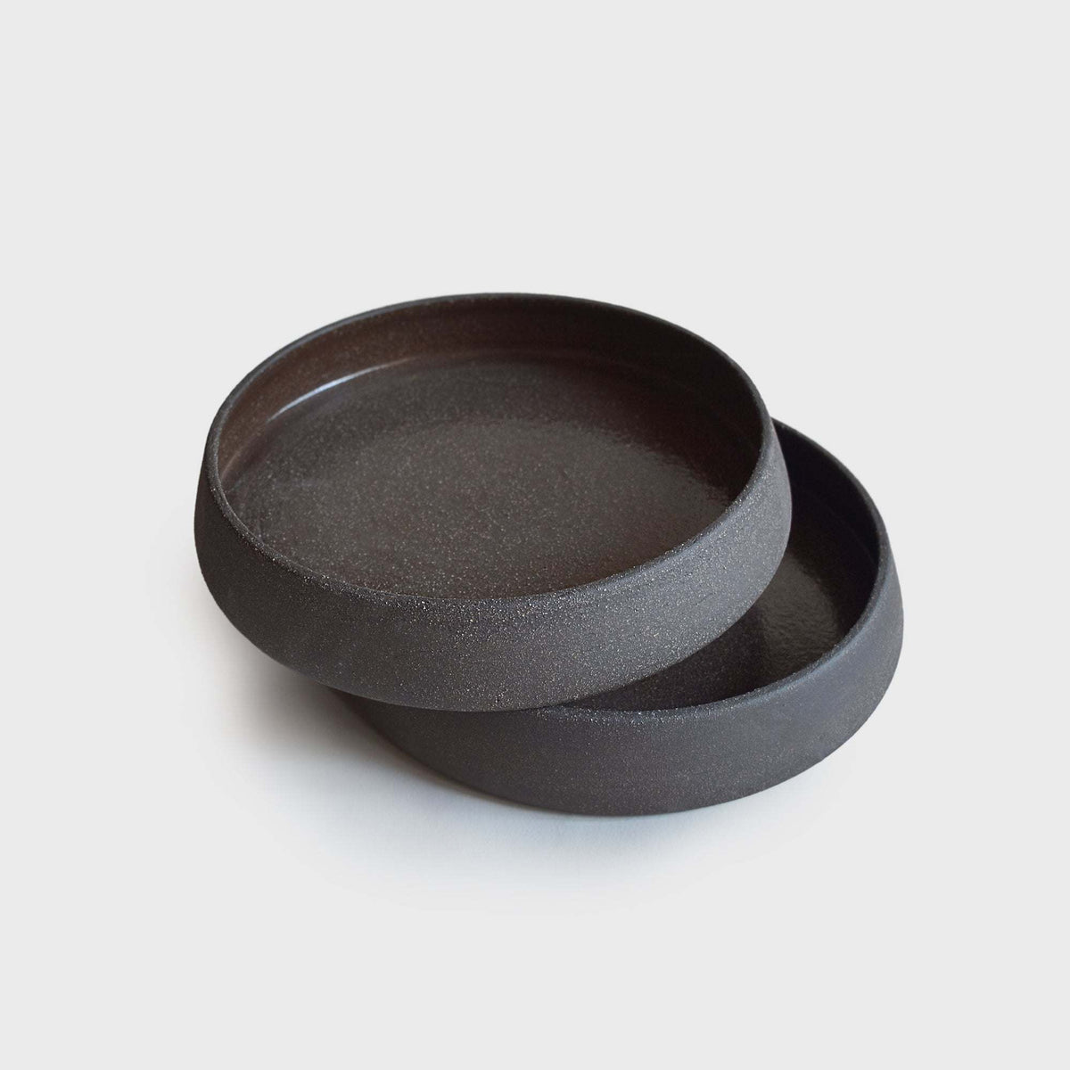Dinner Plates with High Sides in dark charcoal stoneware, with a smooth glazed interior and tall unglazed rim.