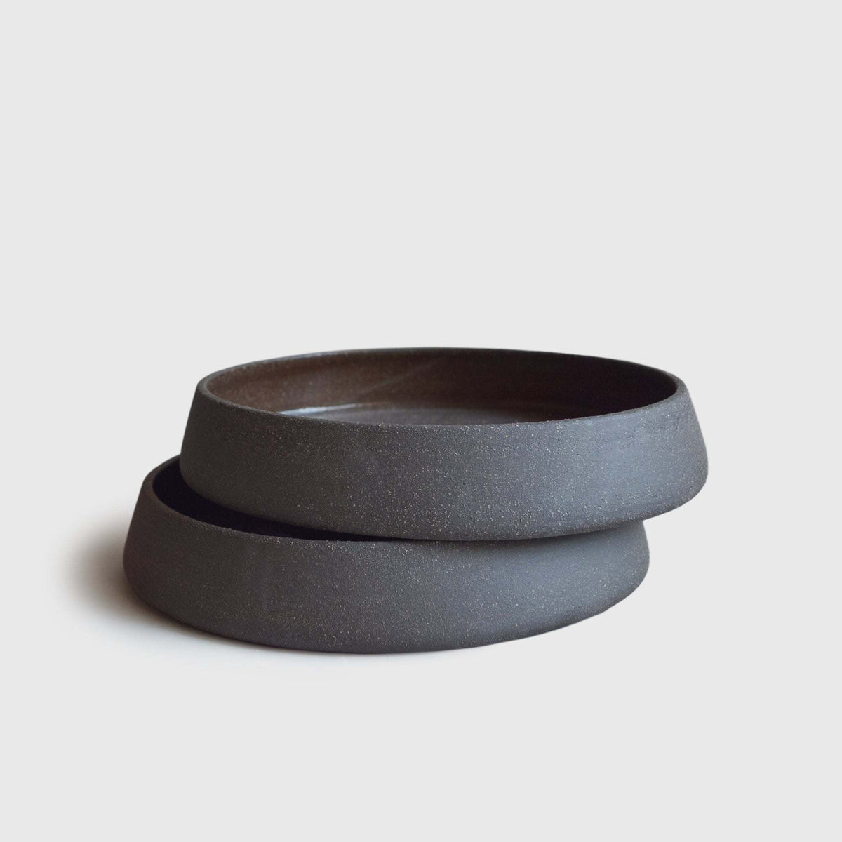 Dinner Plates with High Sides in deep charcoal-brown stoneware, with a smooth dark glaze and raised curved rims.