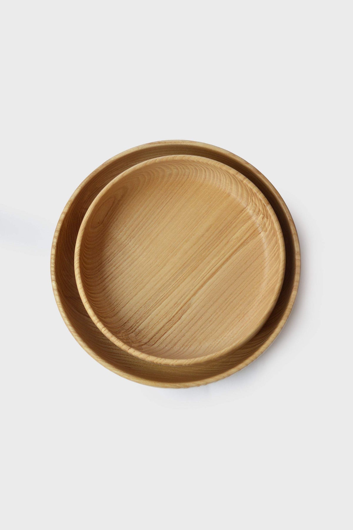 Hand Carved Wooden Plate in natural honey-brown ash wood, with visible grain, a rounded high rim and subtly irregular shape.