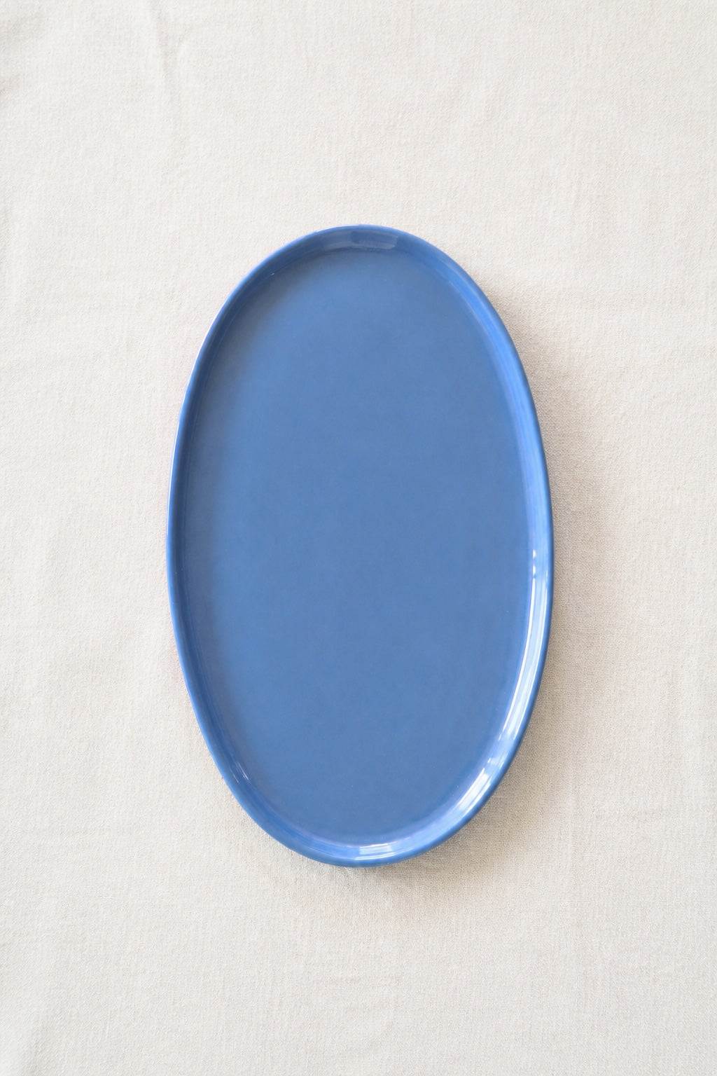 Oval Serving Platter in glossy forget-me-not blue porcelain, with a smooth glaze and softly raised rounded rim.