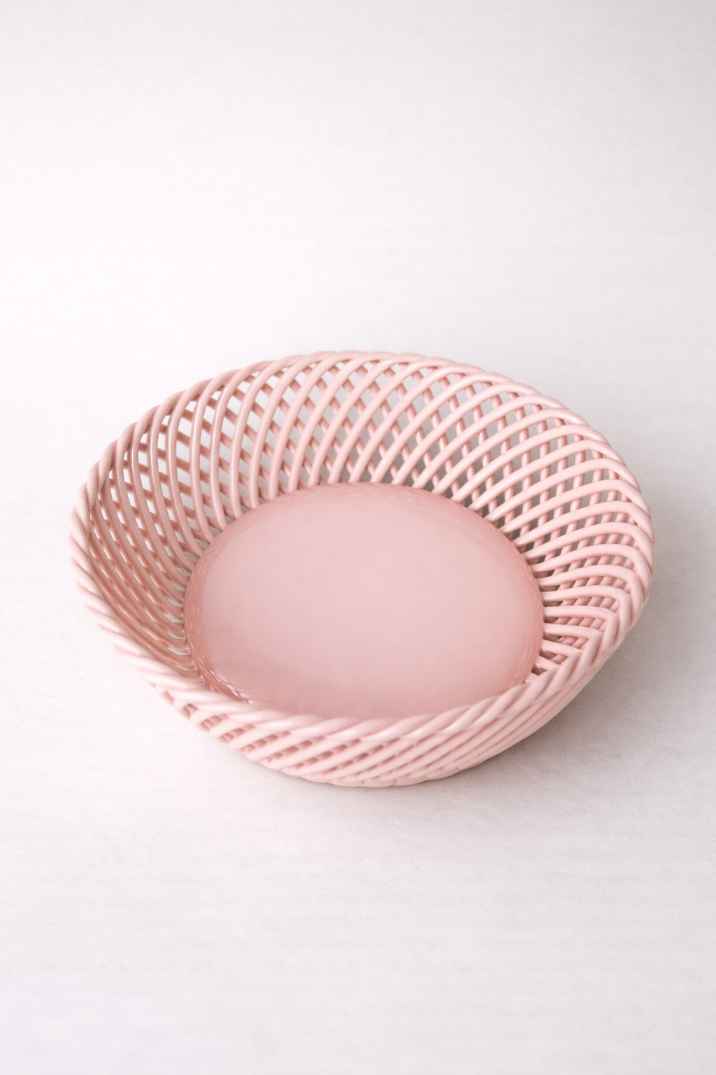 Ceramic Round Hand-Woven Basket in glossy pale pink porcelain, with an open lattice weave and solid round base.