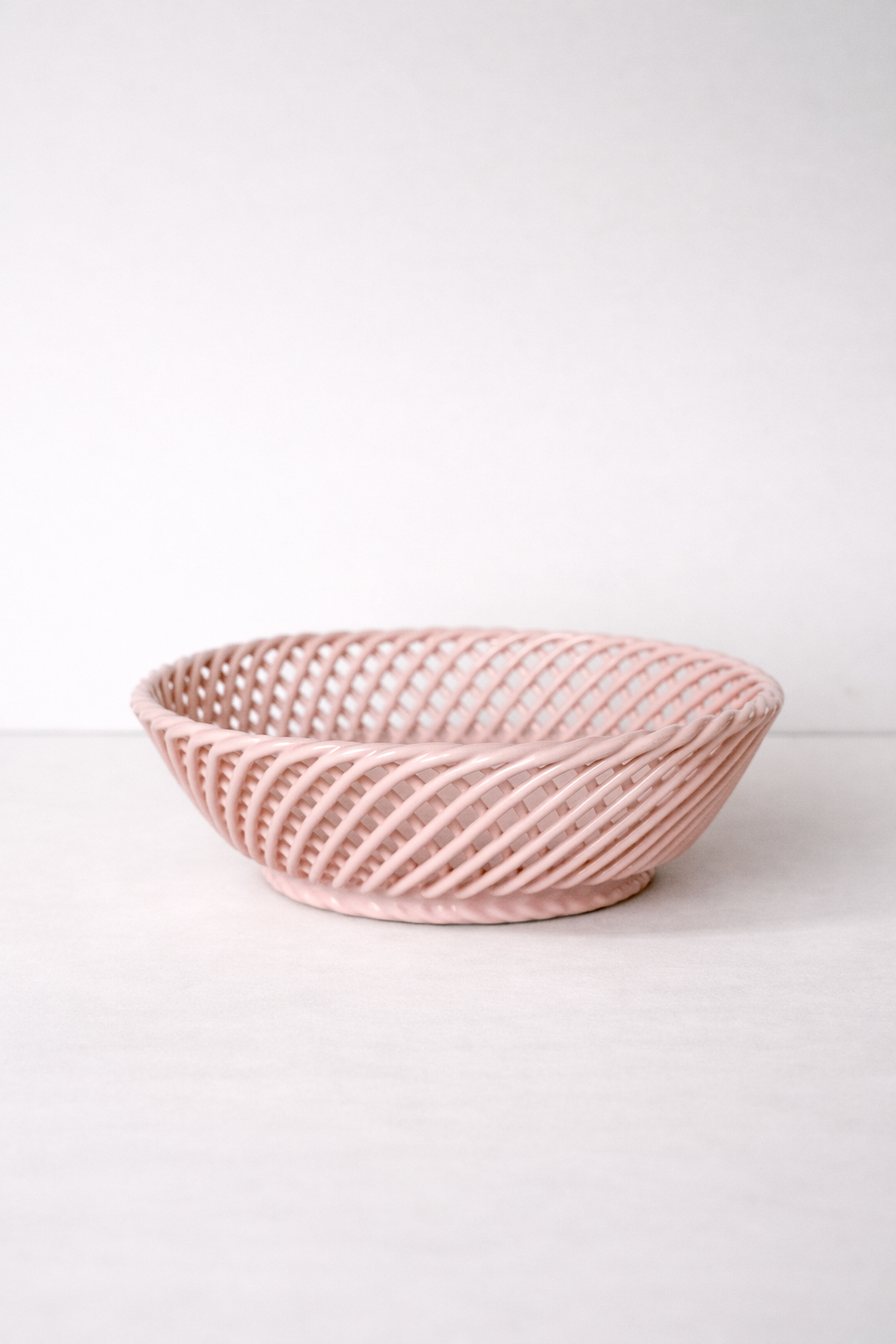 Ceramic Round Hand-Woven Basket in glossy blush pink porcelain, with an airy interlaced design and rounded shape.