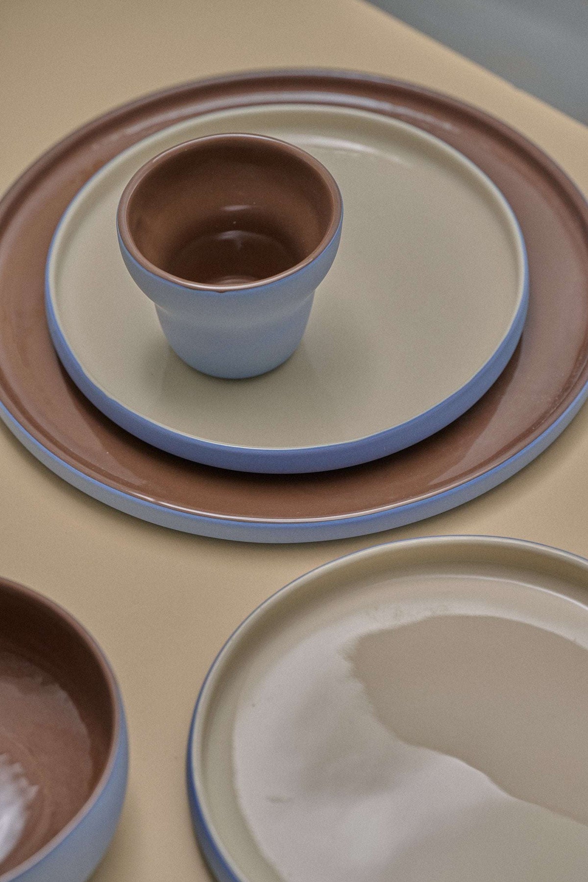 Handmade Blue Porcelain plates with pale blue rims, cream centers, and glossy chocolate-brown glazed exteriors.