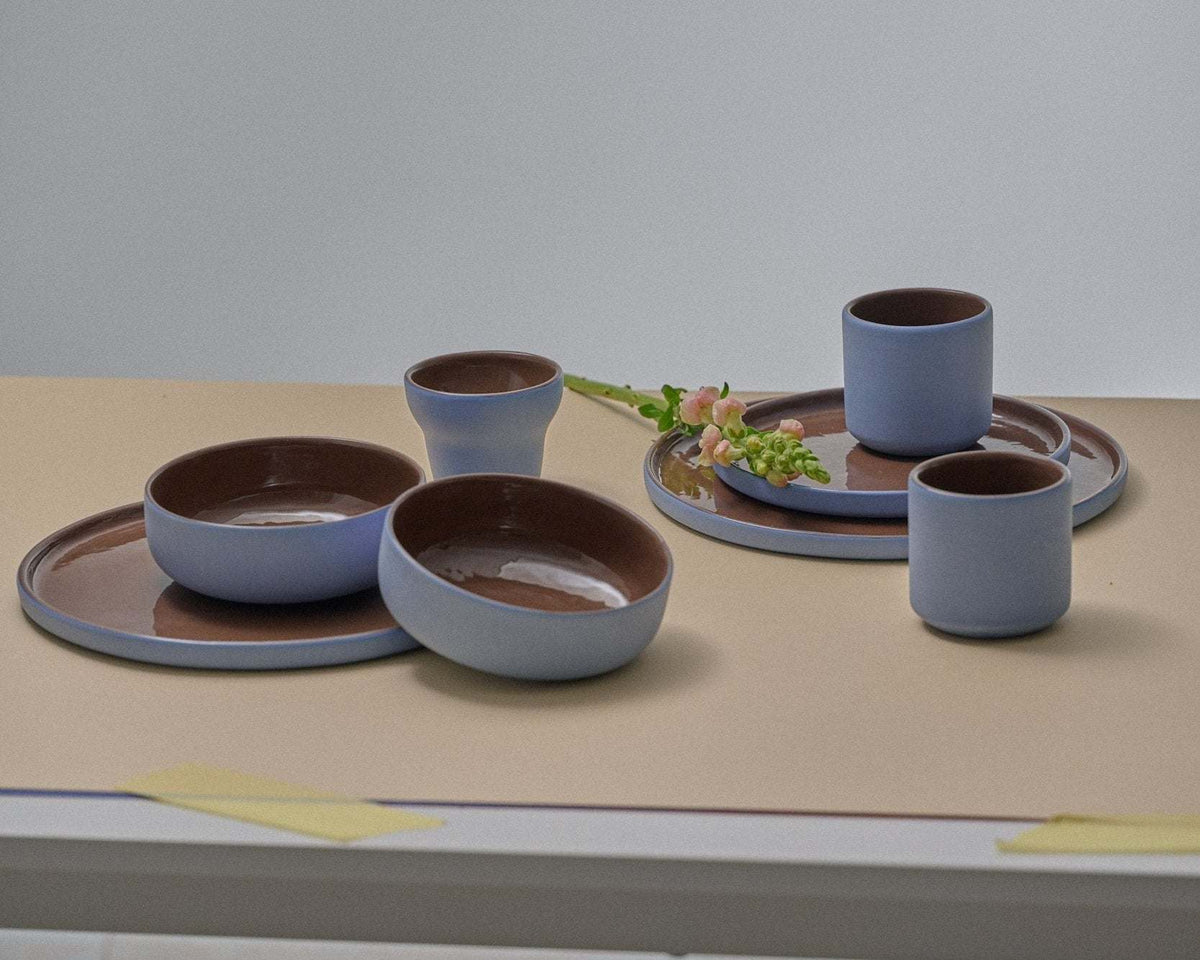 Handmade Blue Porcelain dinner plates with blue exteriors and glossy chocolate-brown interiors, softly rounded rims.
