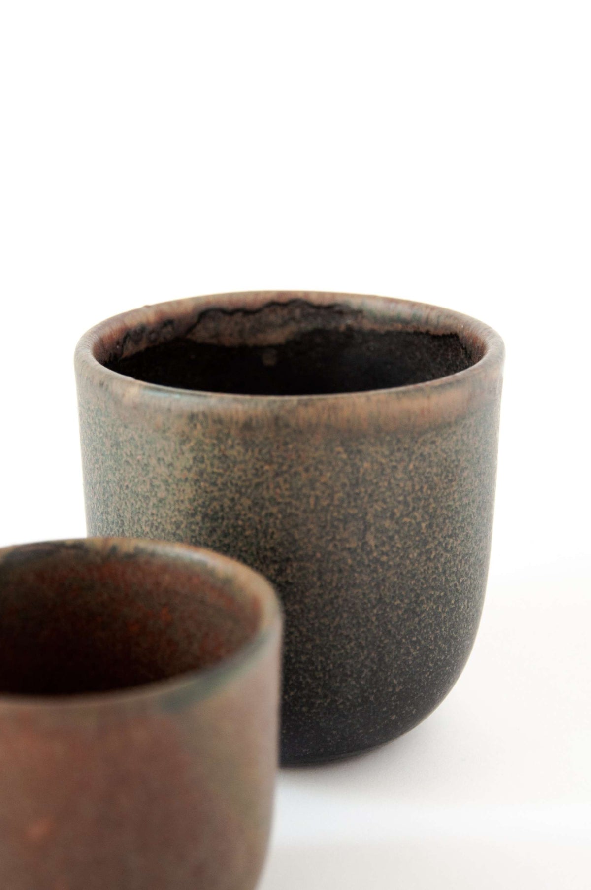 Rust handmade stoneware coffee cup with organic edges and reactive glaze swirl
