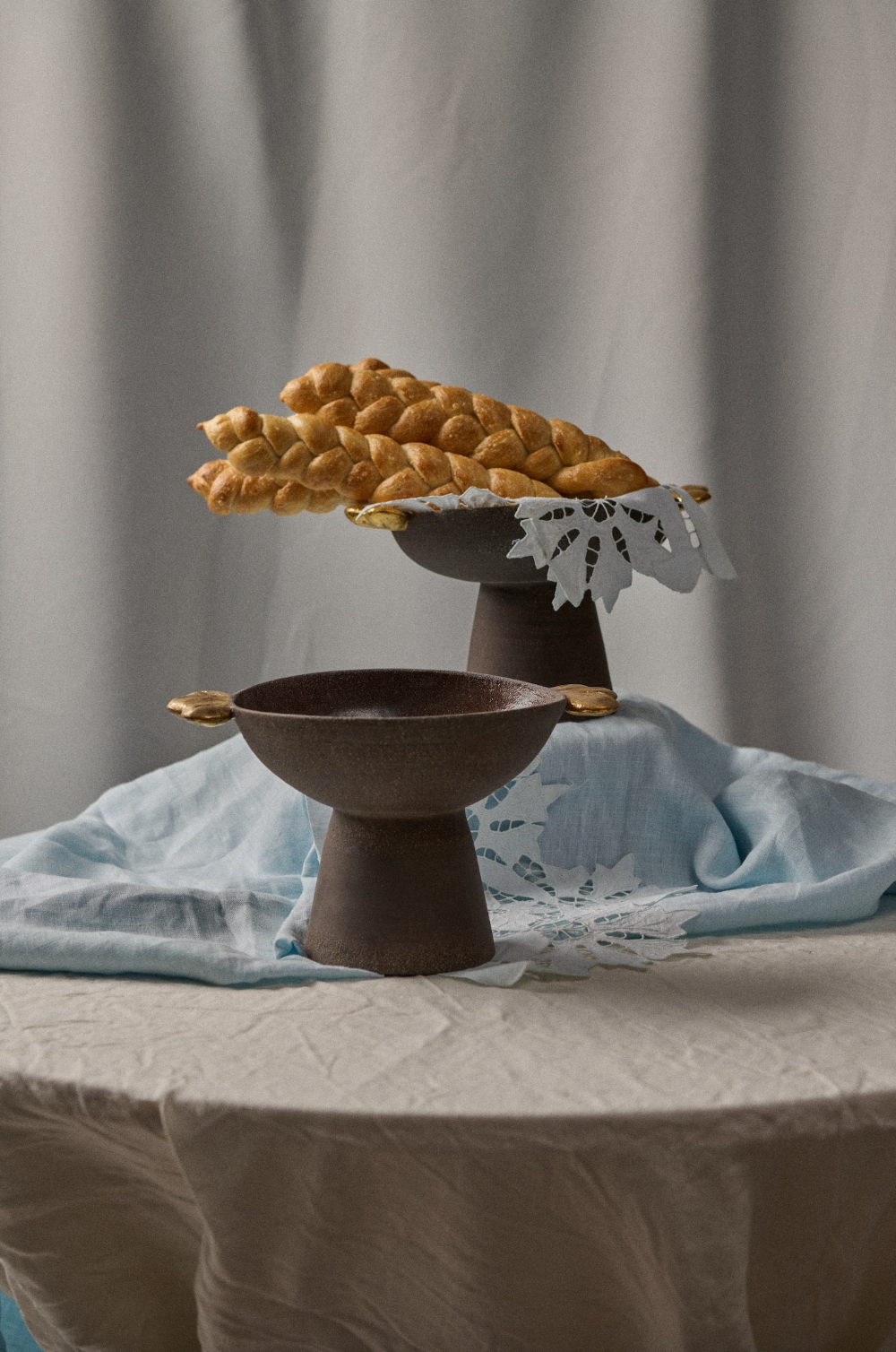 Stoneware pedestal fruit bowl in dark brown with a rough-textured exterior, smooth interior, and small gold leaf accents.