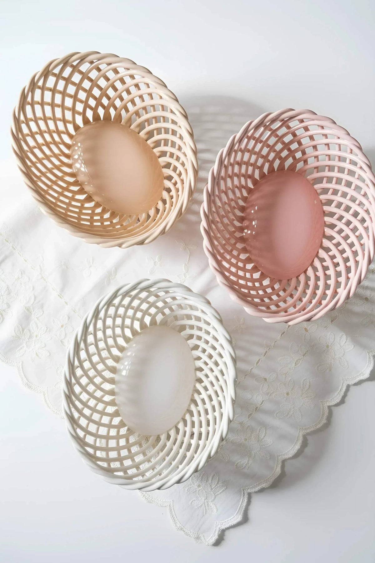 Hand-Woven Ceramic Basket set of three glossy porcelain dishes in beige, pink, and white with woven open lattice sides.