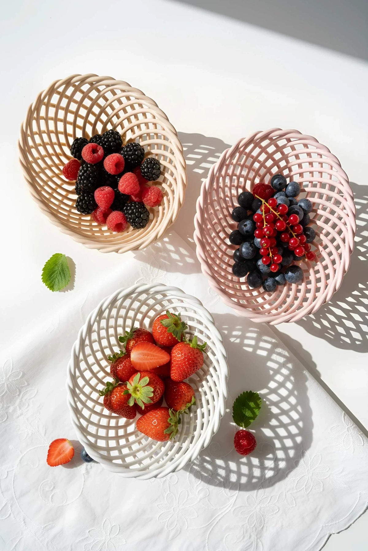 Hand-Woven Ceramic Basket in cream, blush pink, and white glazed porcelain, with airy woven lattice sides and oval shape.