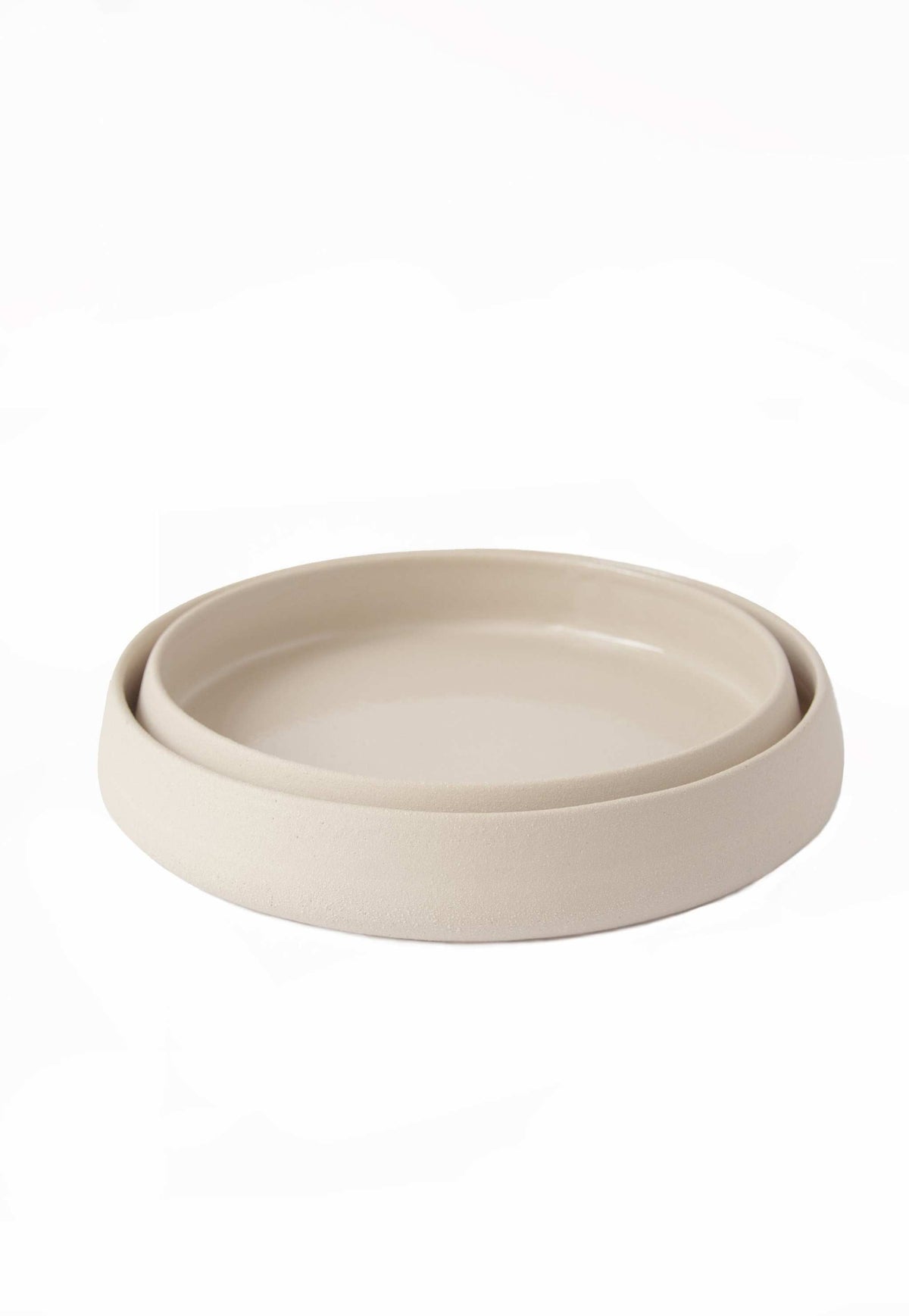 Handmade stoneware dinner plates with high sides and transparent glaze, showcasing rustic texture and glossy interior