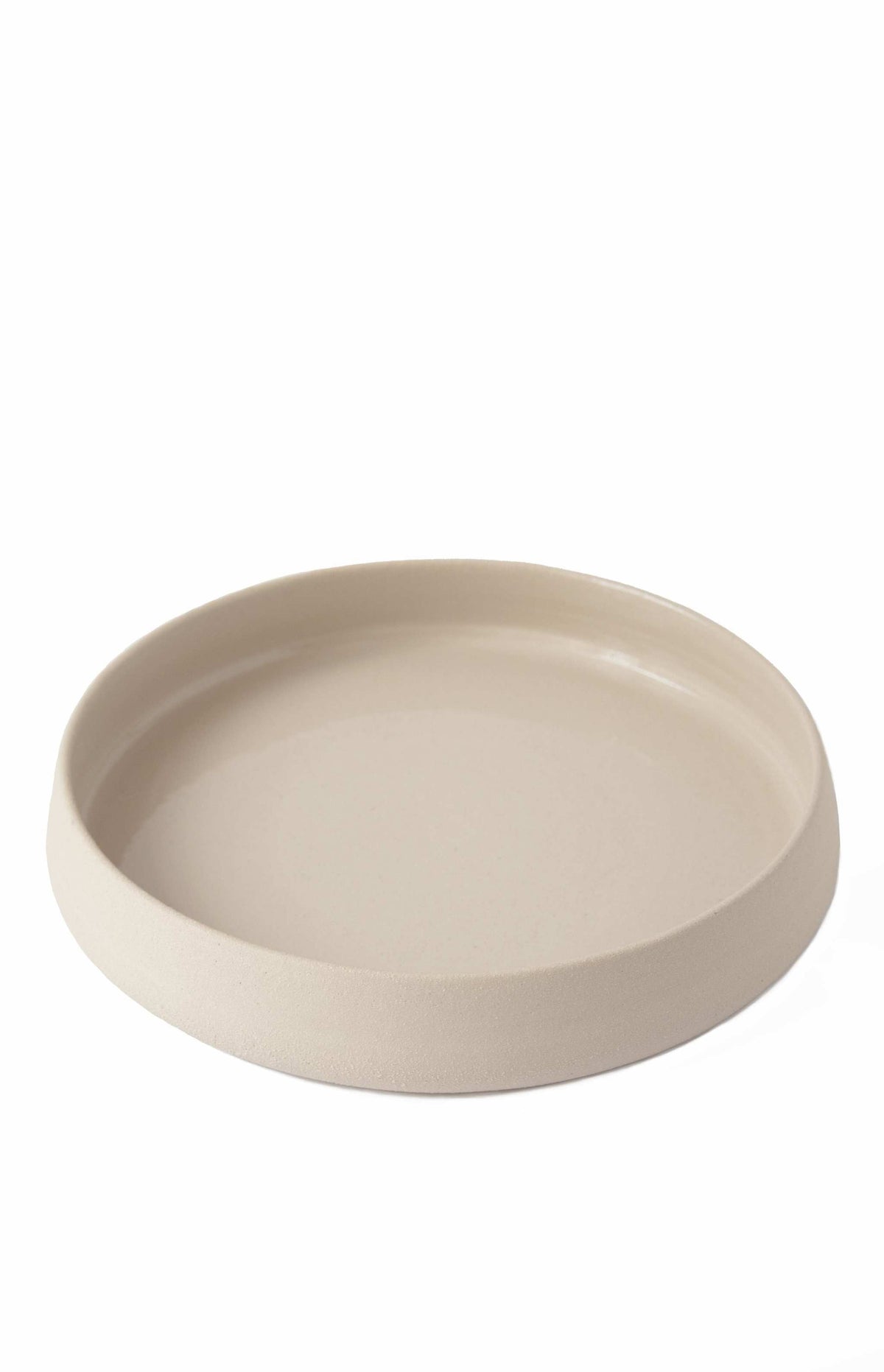 Handmade stoneware dinner plates with high sides and transparent glaze showing rustic texture and glossy interior