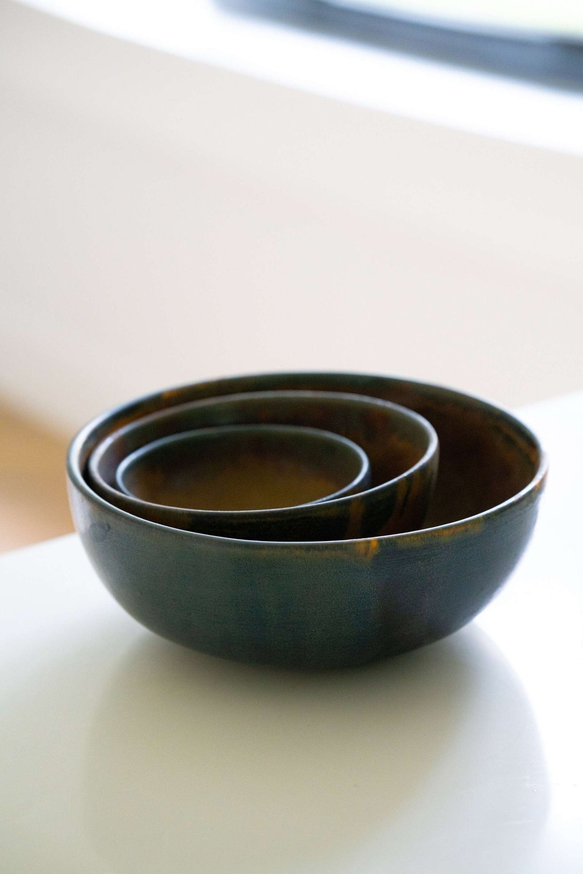 Rust stoneware nesting bowl set with matte brown-black glaze, hand-made and stackable, showcasing earthy pottery design